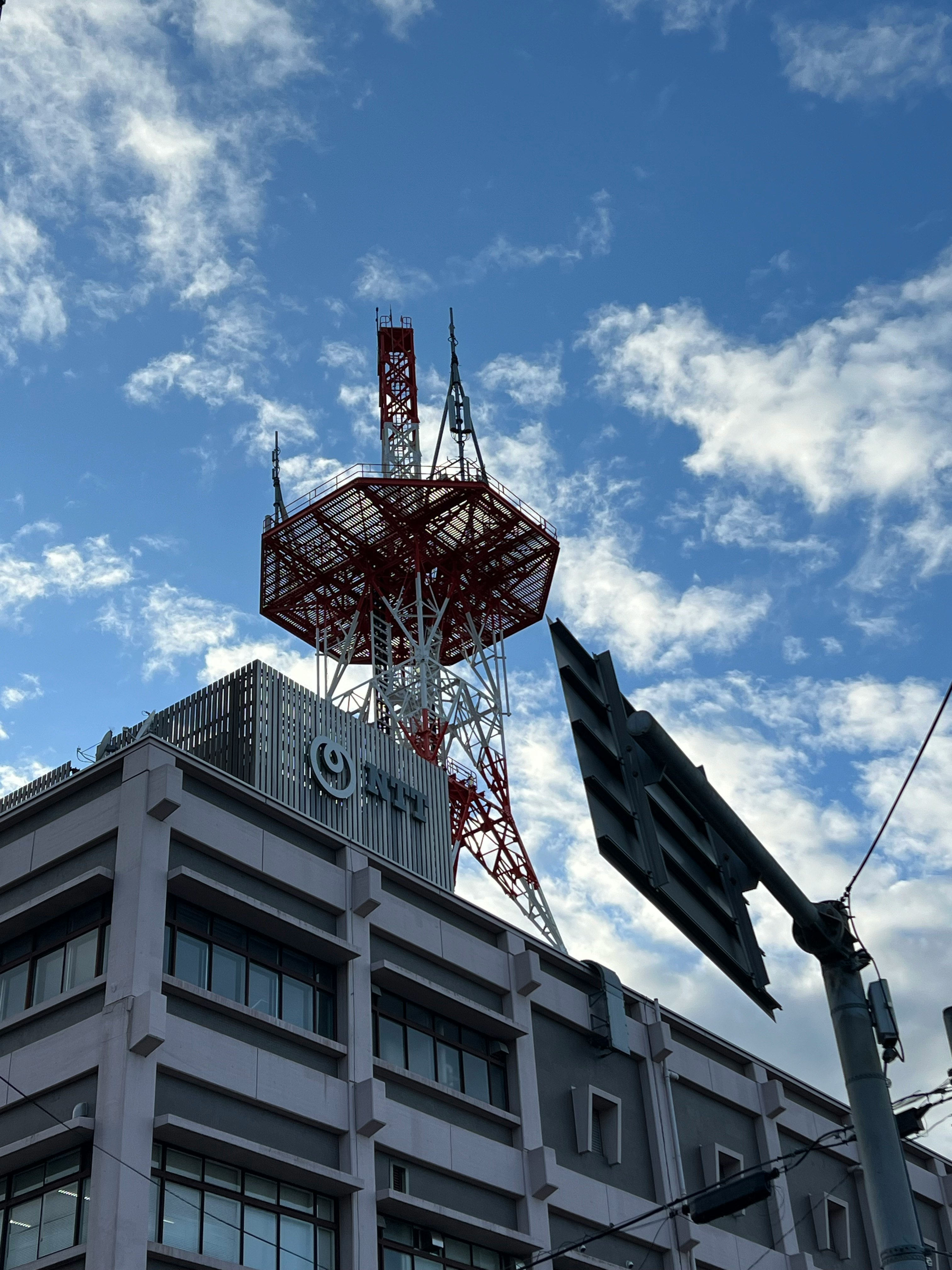 青空の下にそびえる鉄塔と通信設備のある建物