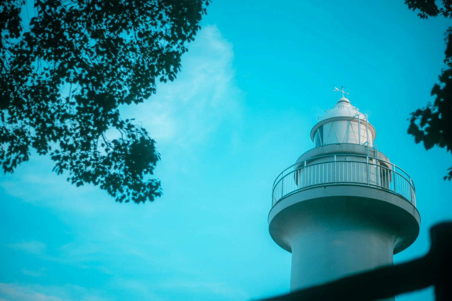 Foto di un faro contro un cielo blu con alberi circostanti