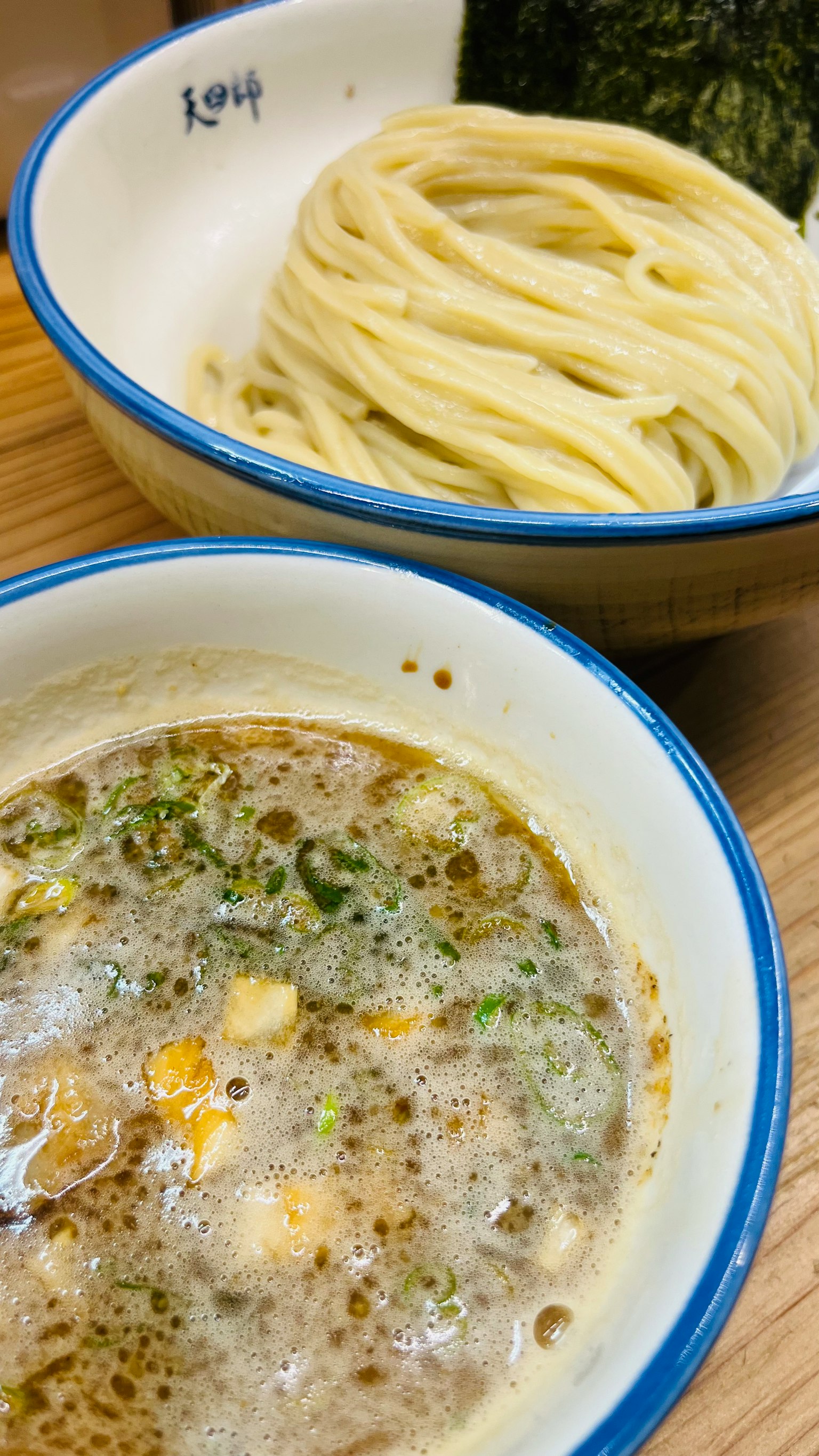 A bowl of creamy broth served with a side of noodles and seaweed