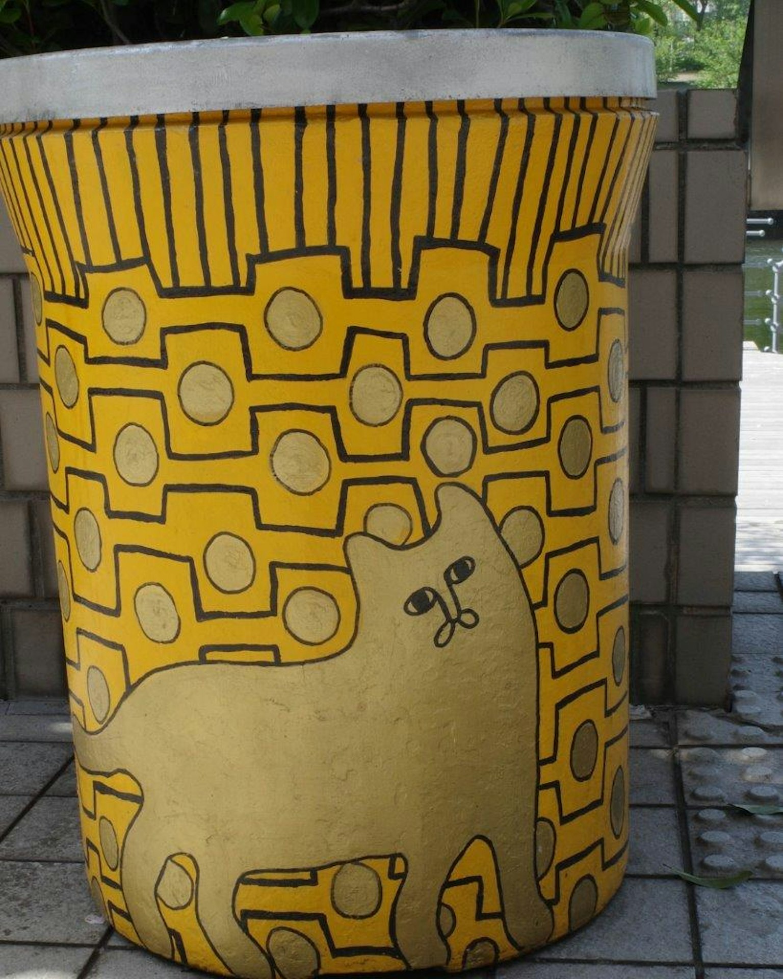 Yellow cylindrical object featuring a cat illustration and geometric patterns