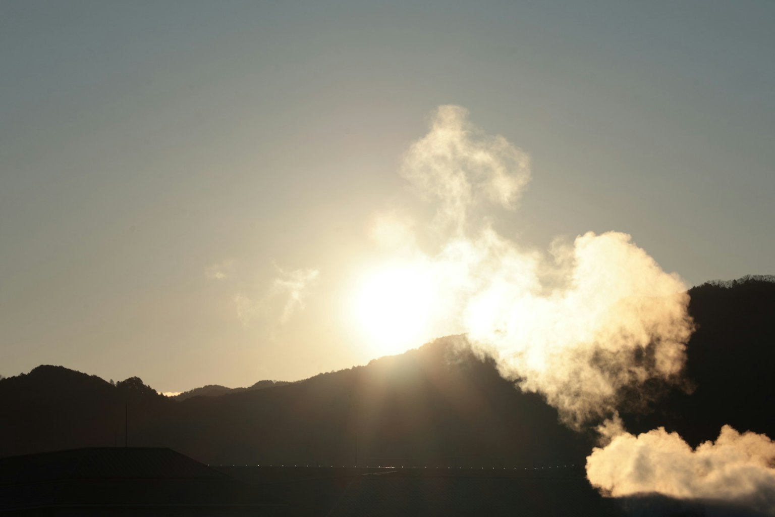 Alba dietro le montagne con vapore in primo piano