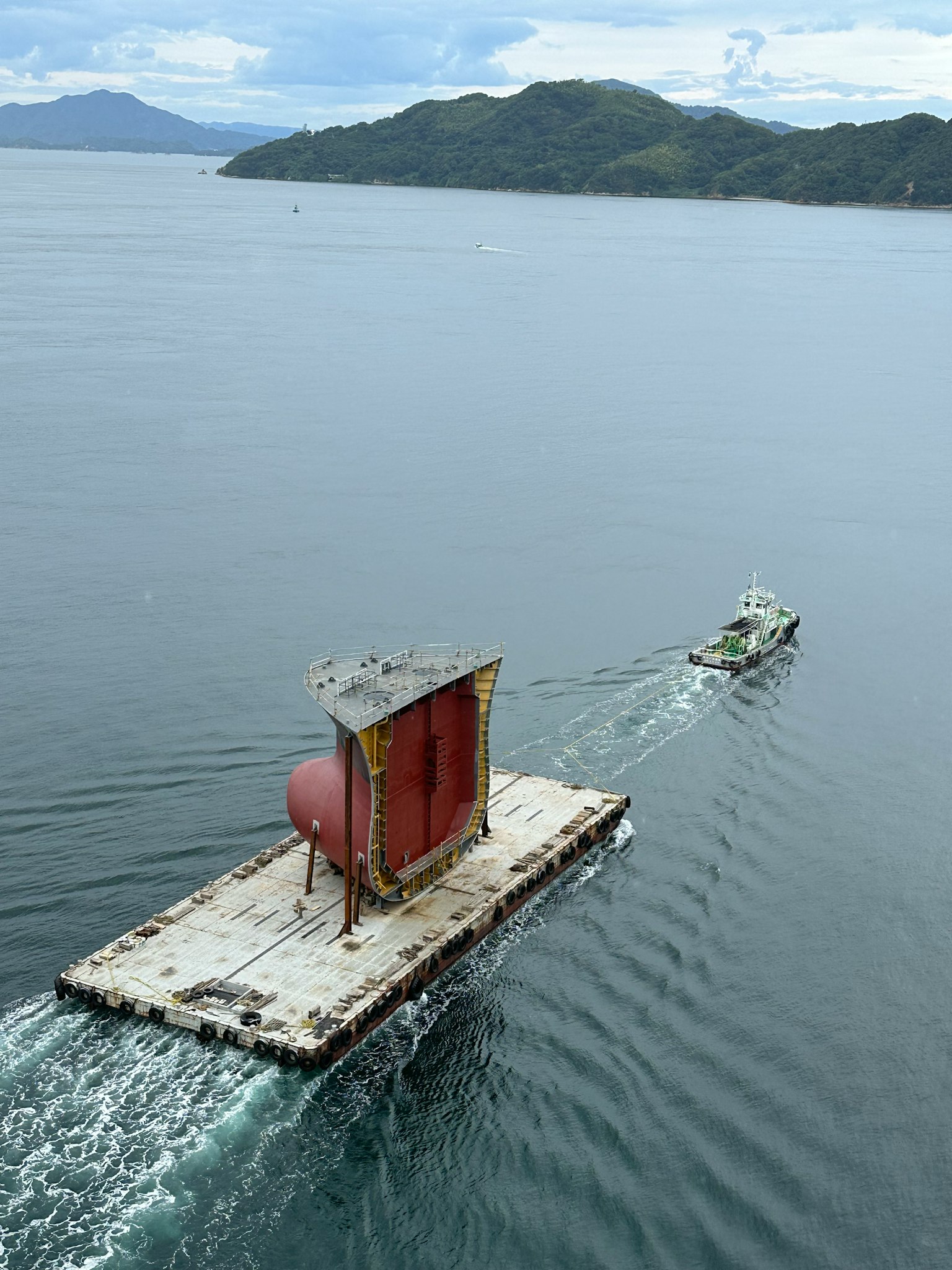 Una gran estructura cilíndrica remolcada por un pequeño bote en el agua
