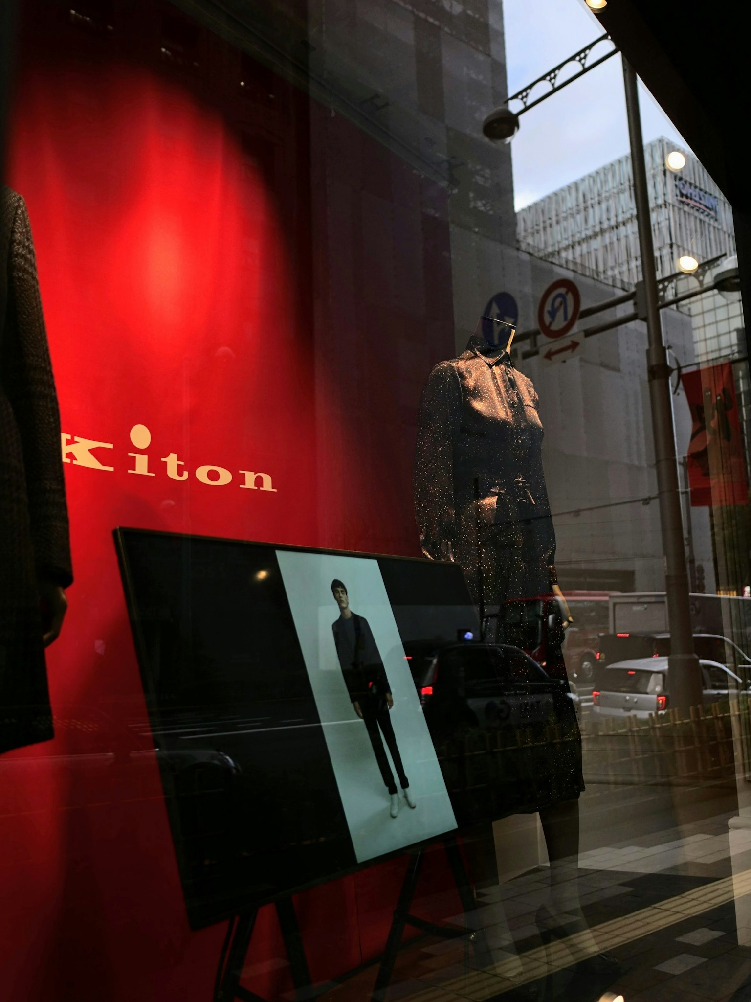 Vitrine de Kiton présentant des vêtements avec un fond rouge