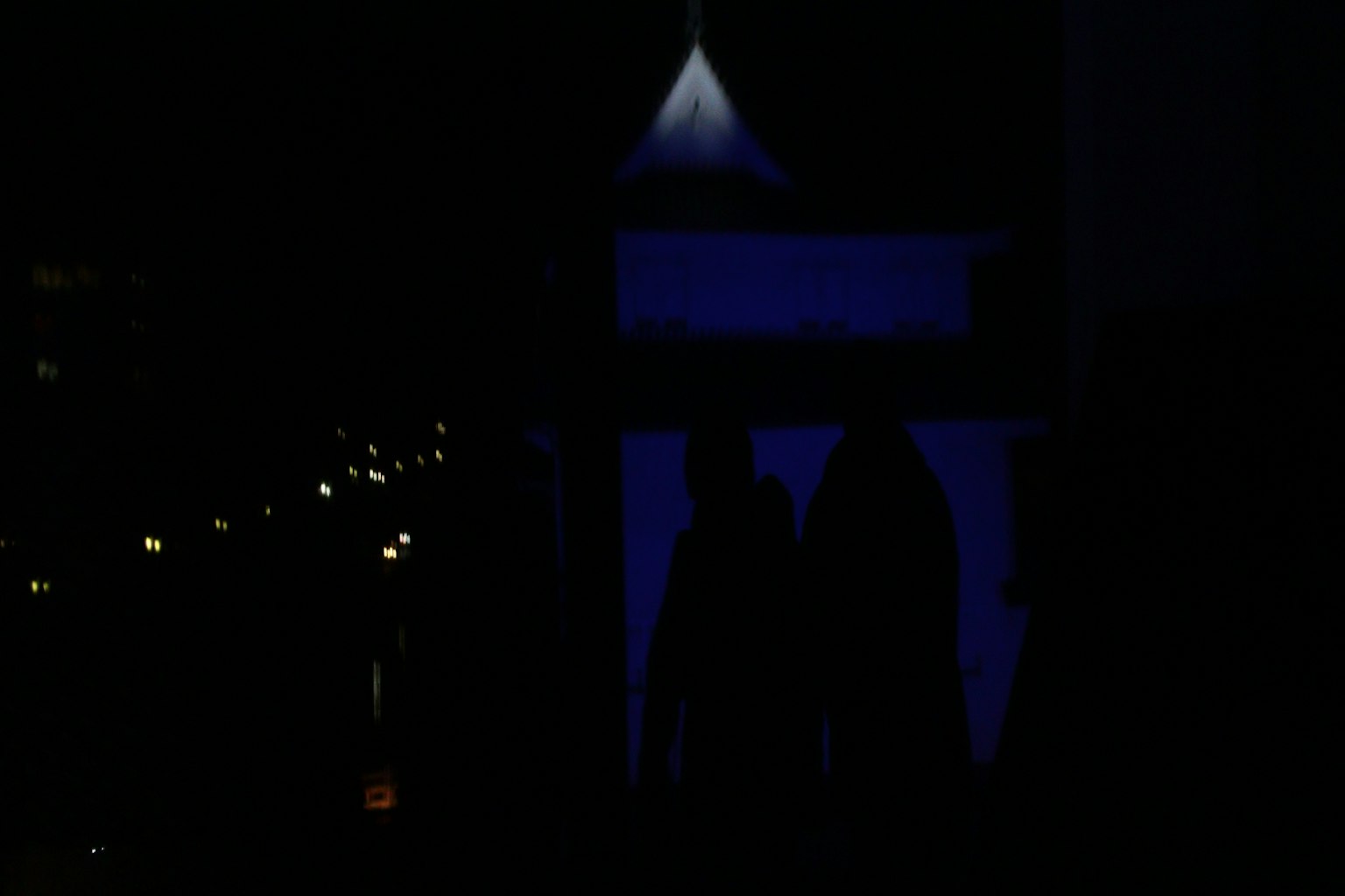 Silhouette di persone su sfondo scuro con una struttura illuminata di blu
