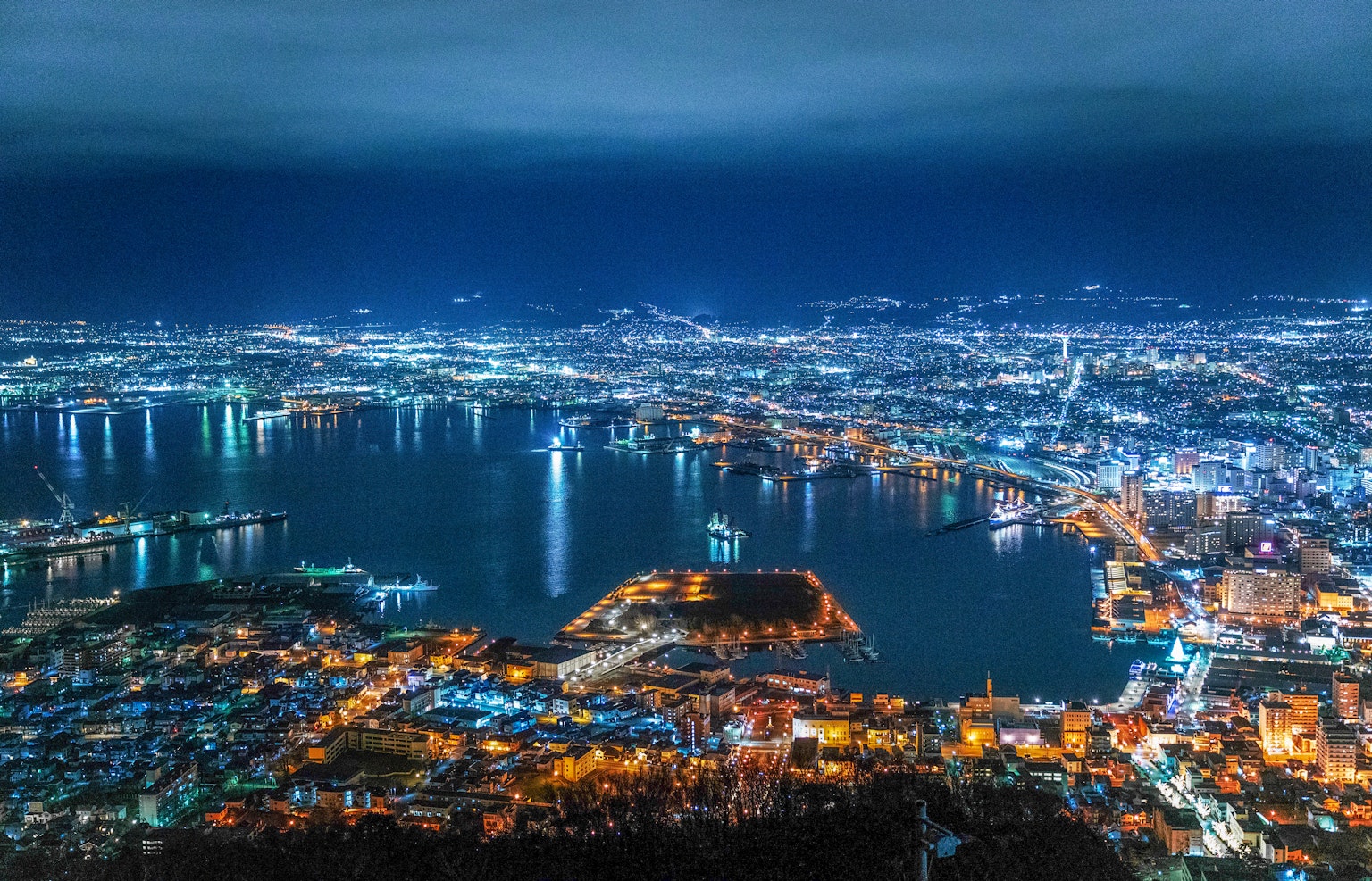 Beeindruckende Panoramaansicht einer Hafenstadt bei Nacht