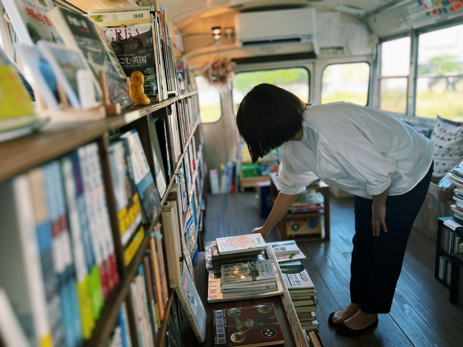 Woman browsing books inside a bus filled with shelves of various books