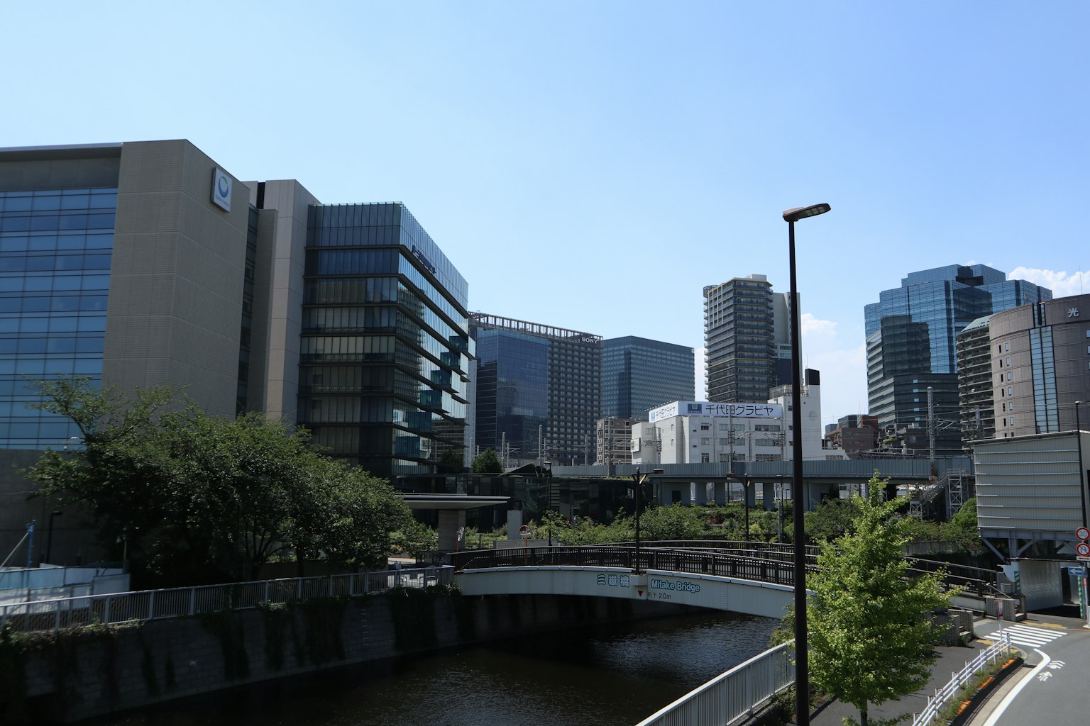 Skyline urbaine avec des bâtiments hauts et une rivière sous un ciel bleu clair avec des arbres verts