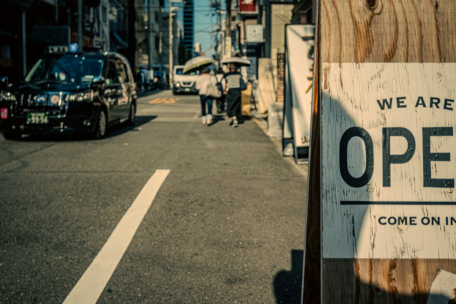 Straßenszene mit einem offenen Schild Autos und Fußgänger gehen