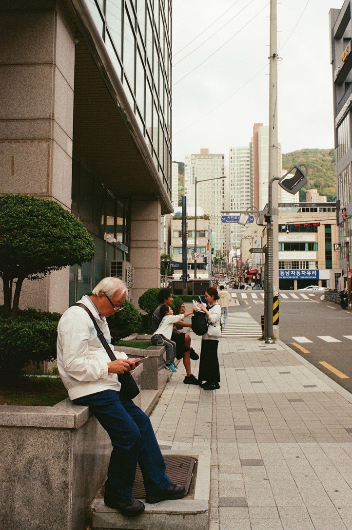 ビルの路地で立ち話する人々とベンチのある歩道