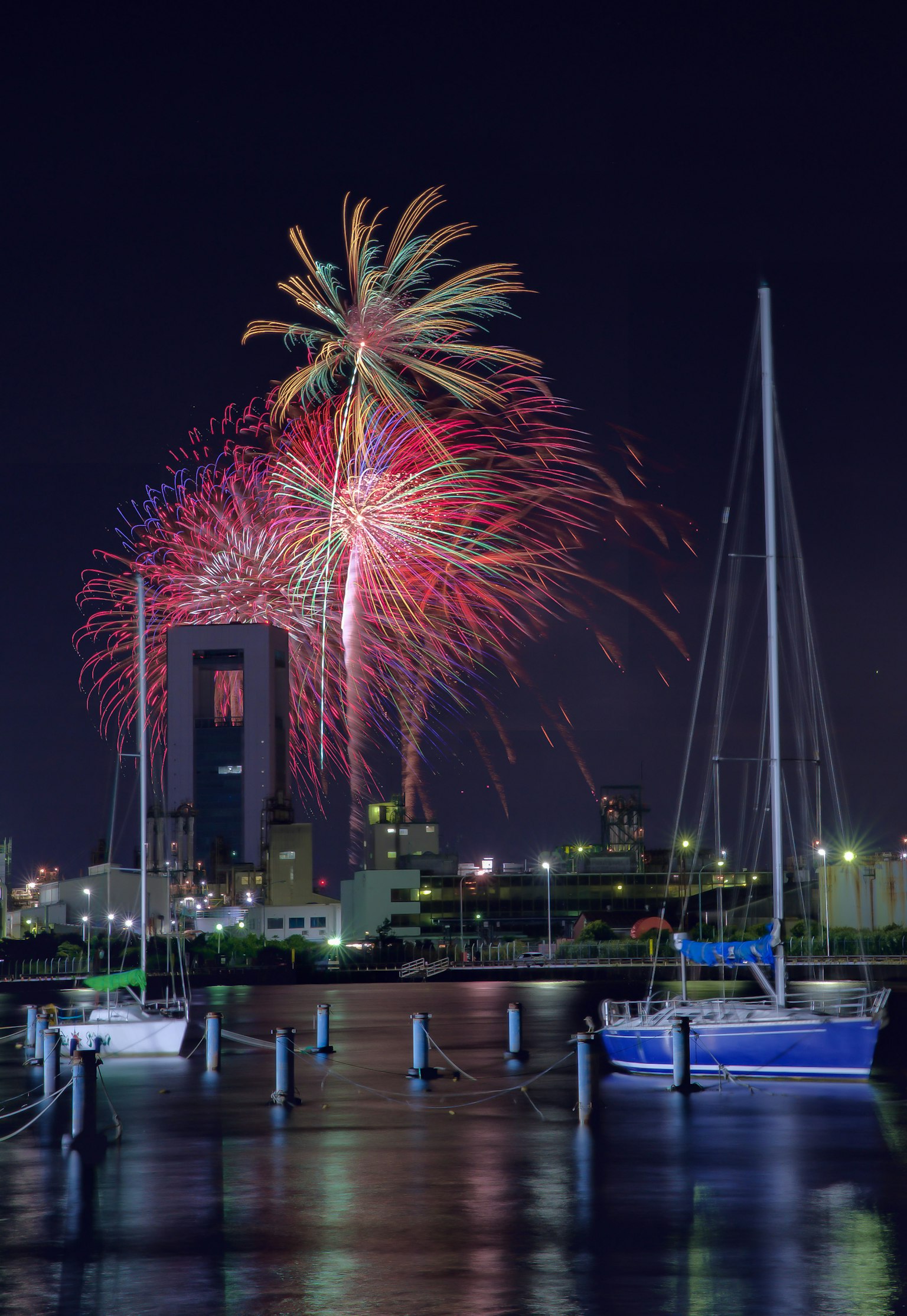 Spettacolo di fuochi d'artificio colorati sopra un porto turistico di notte