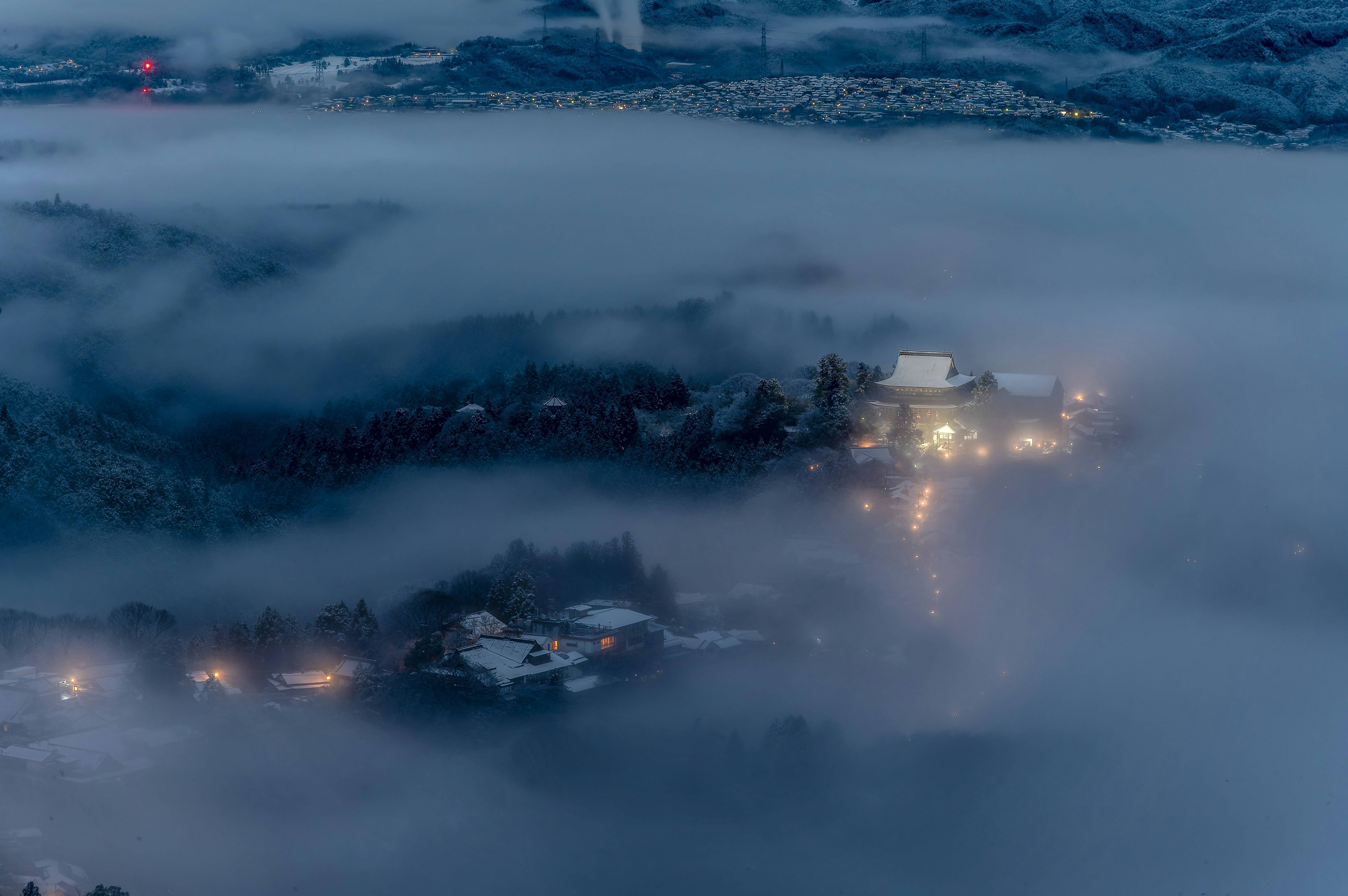 雲海に浮かぶ雪景色の山里と灯りの集落の夜景