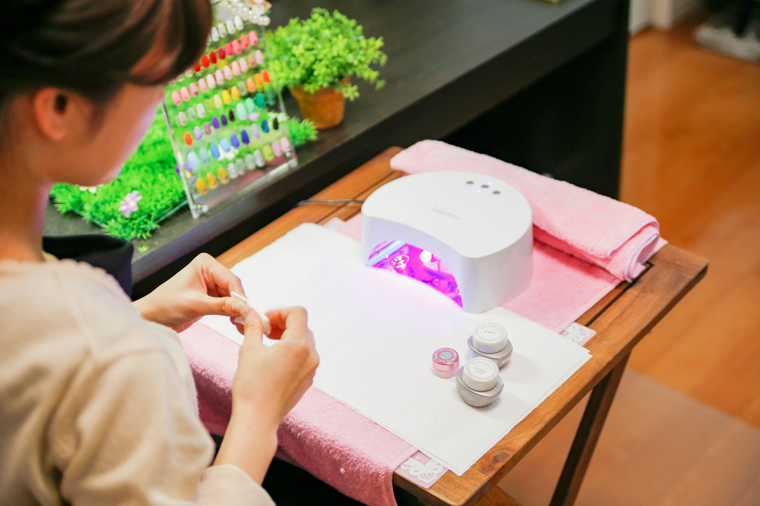 女性在美甲店使用紫色UV灯涂抹指甲油