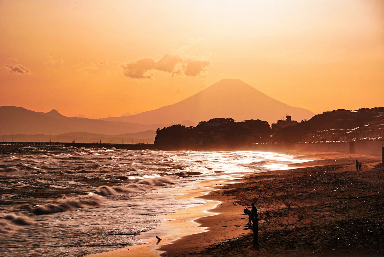 Spiaggia al tramonto con silhouette del Monte Fuji