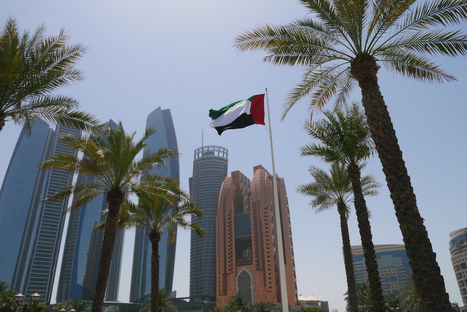 Vista cittadina con la bandiera degli Emirati Arabi Uniti palme e grattacieli sullo sfondo