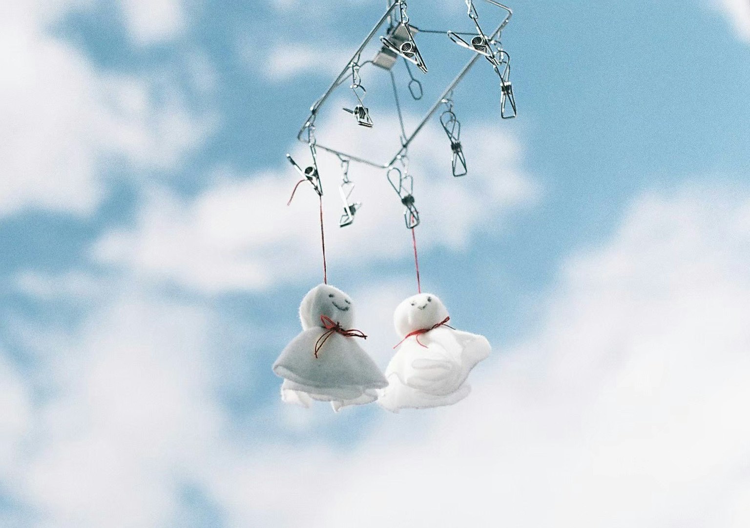 White plush ducks hanging against a blue sky