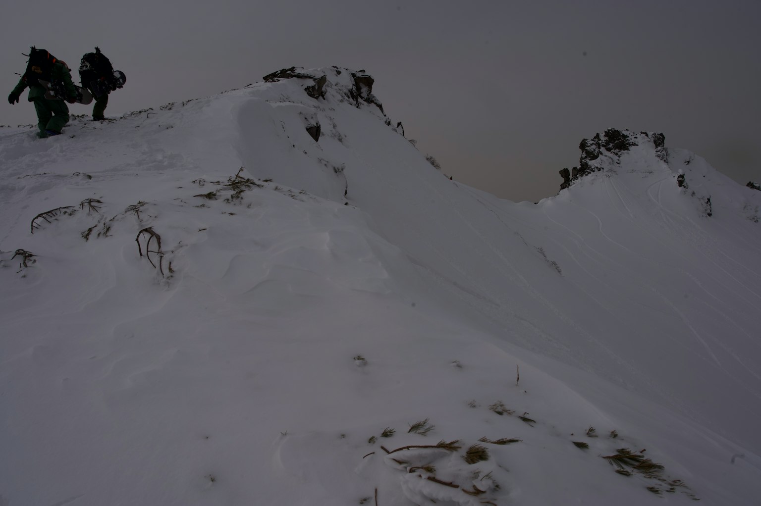 登山者在陰雲密布的天空下穿越一個被雪覆蓋的山峰