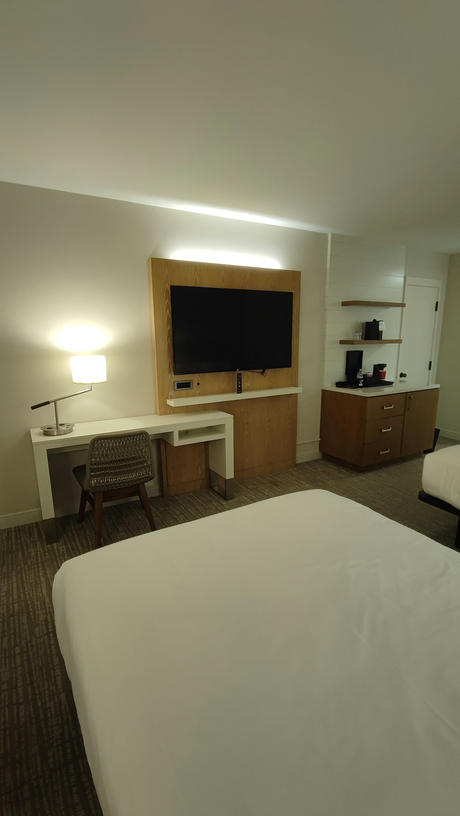 Kamar hotel sederhana dan modern dilengkapi meja kursi dan TV dinding