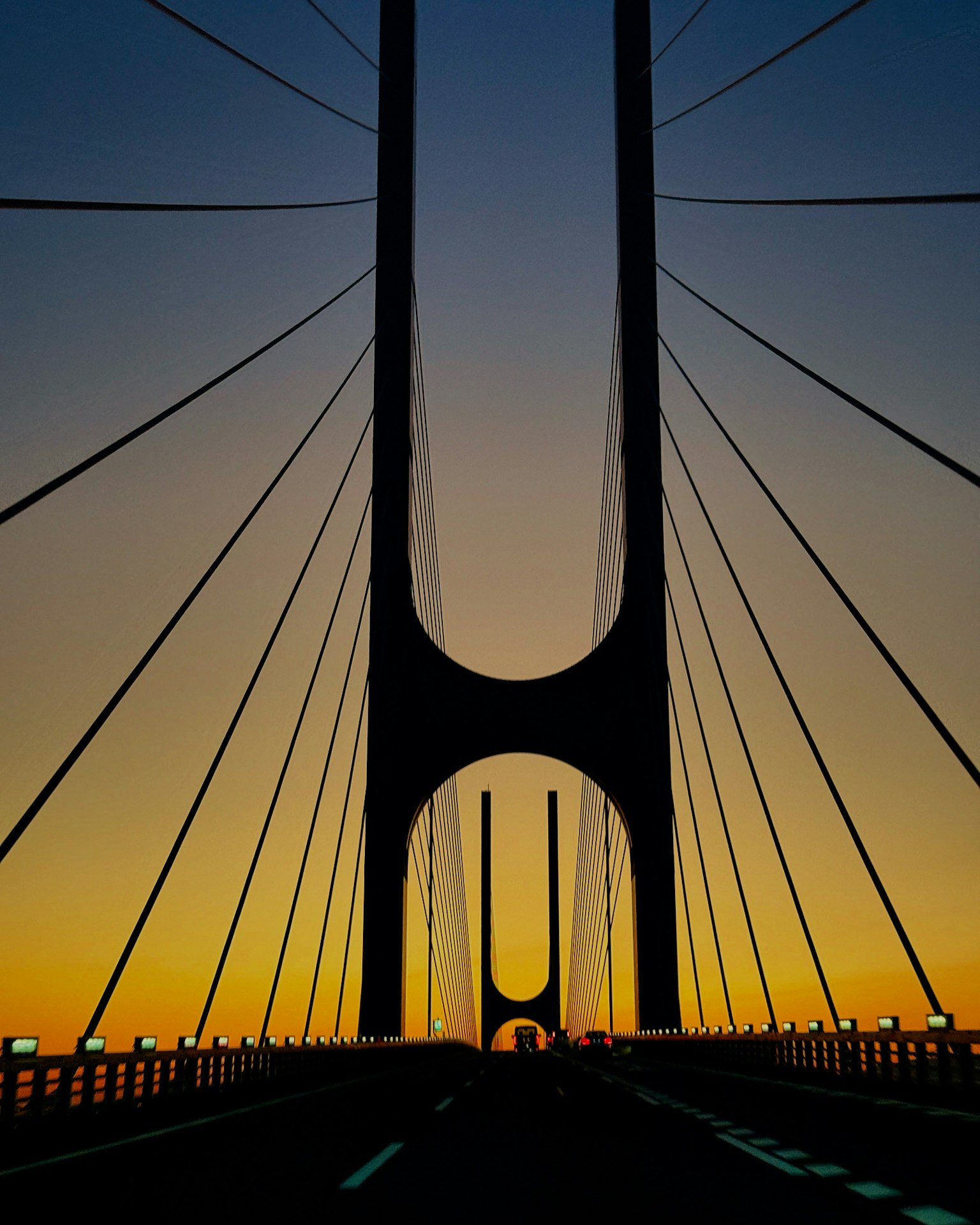 Silhouette of a bridge at sunset with cables