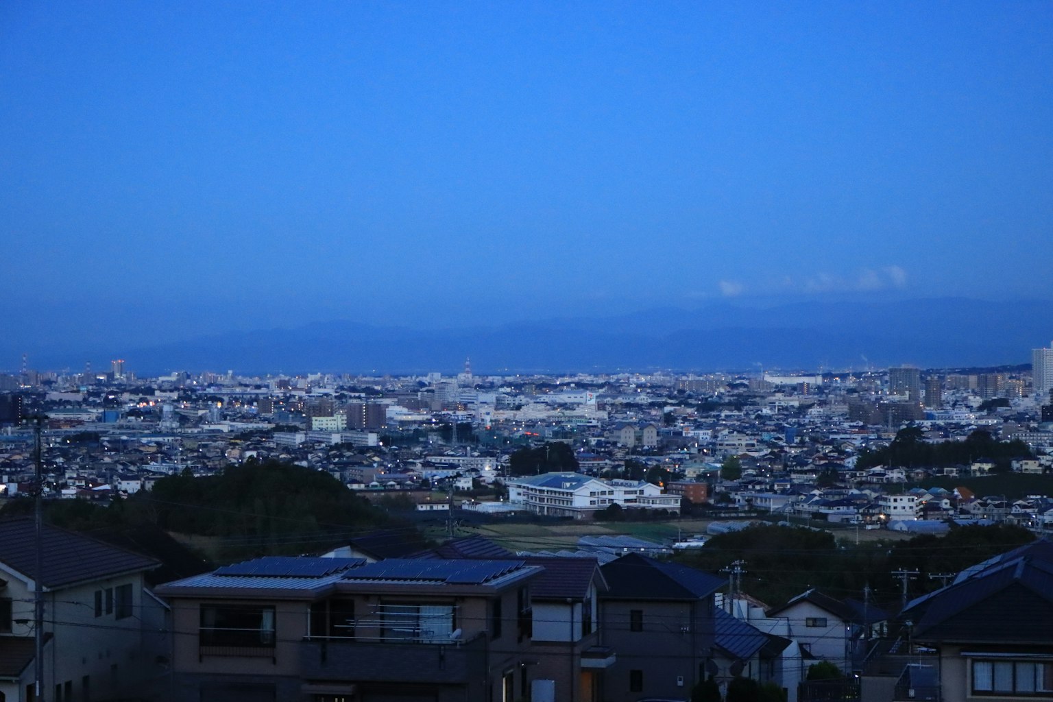 Paisaje urbano bajo un cielo azul con casas y montañas distantes