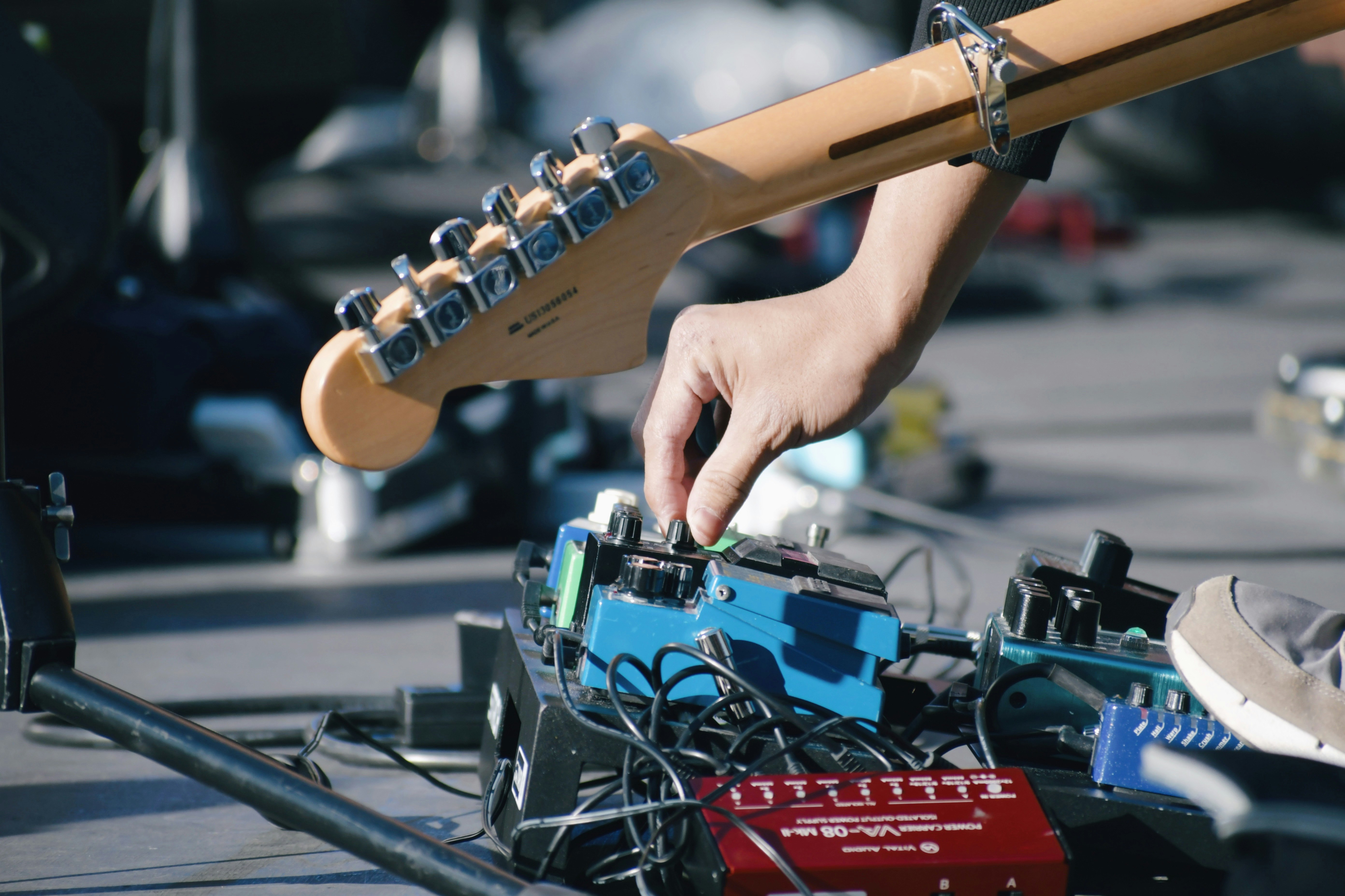 ギターのヘッドと手元で調整する音楽機材の作業風景