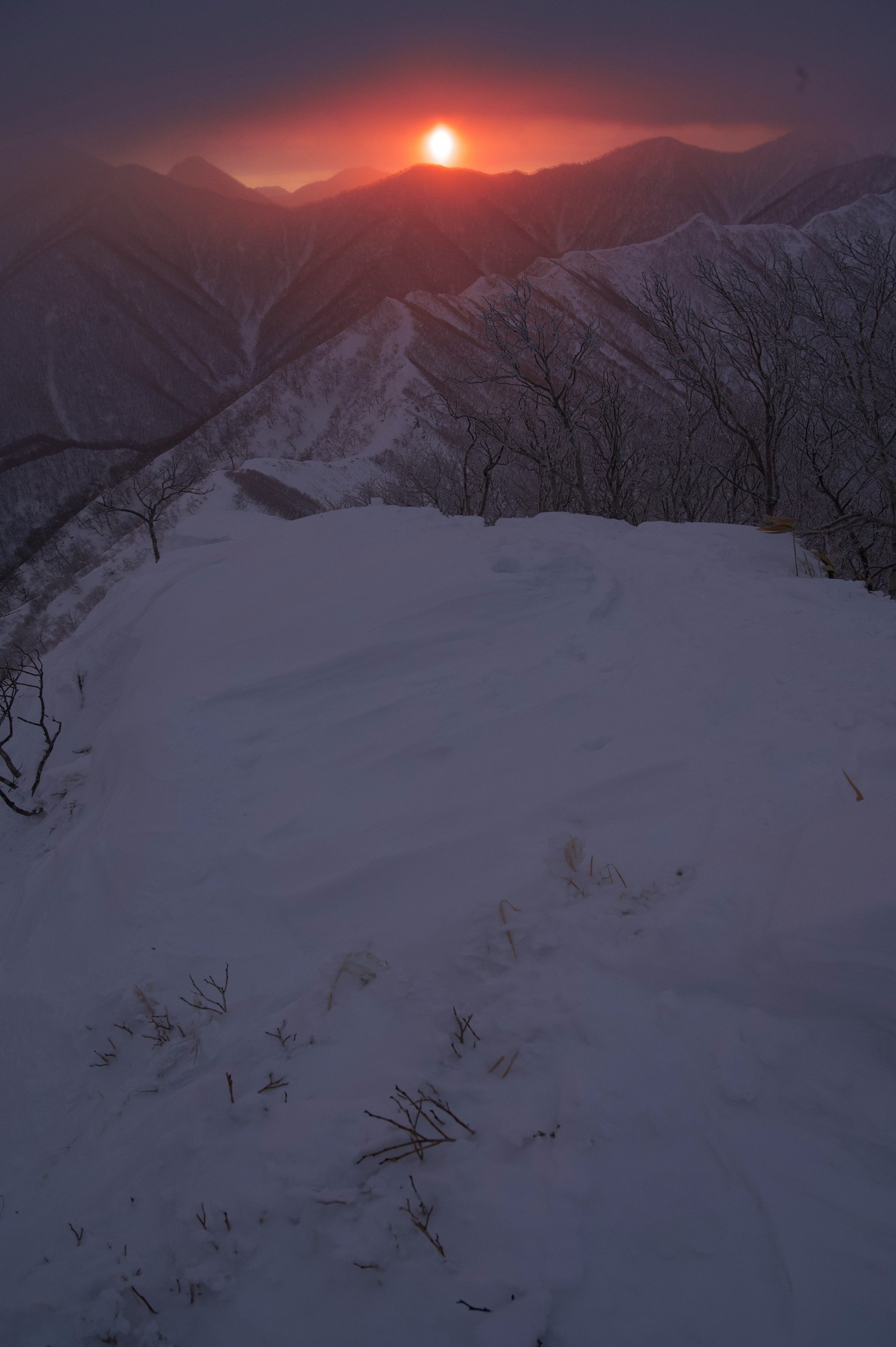 Vista del sole che sorge sopra le vette montuose innevate