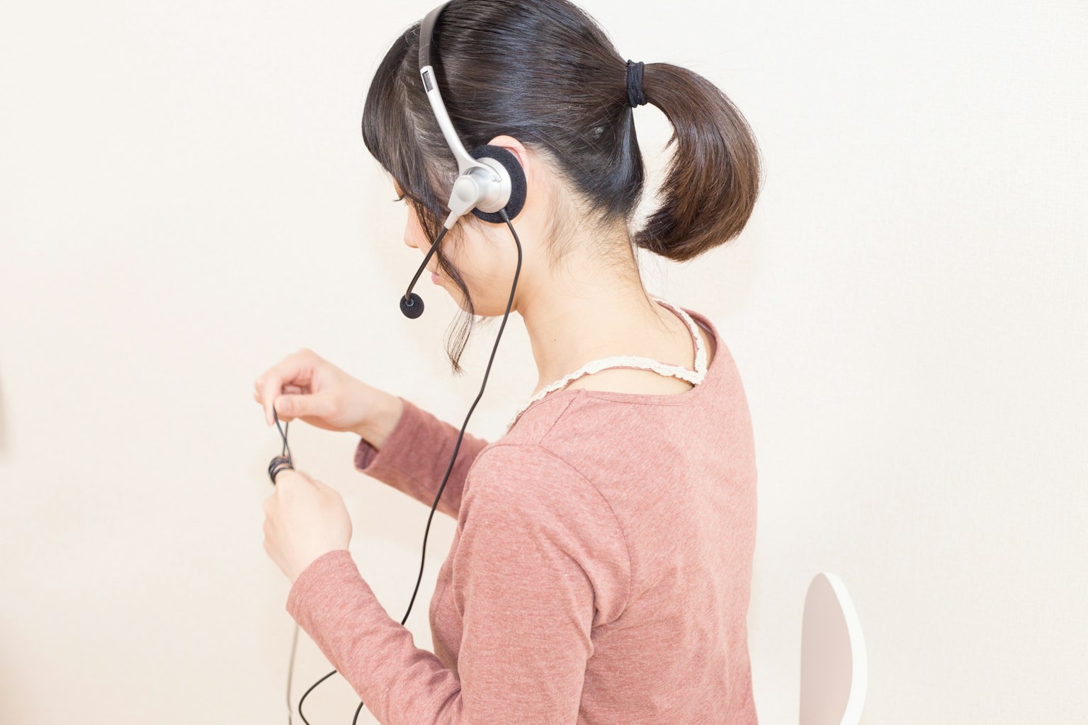 Woman wearing a headset adjusting the cord