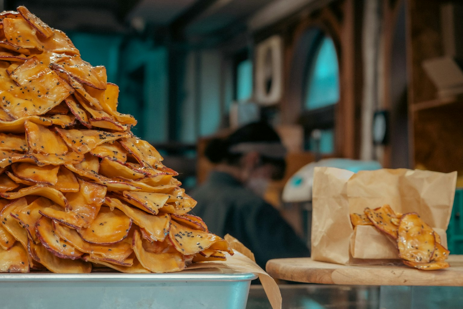Tumpukan besar keripik pisang goreng dengan camilan kecil yang dibungkus di atas meja