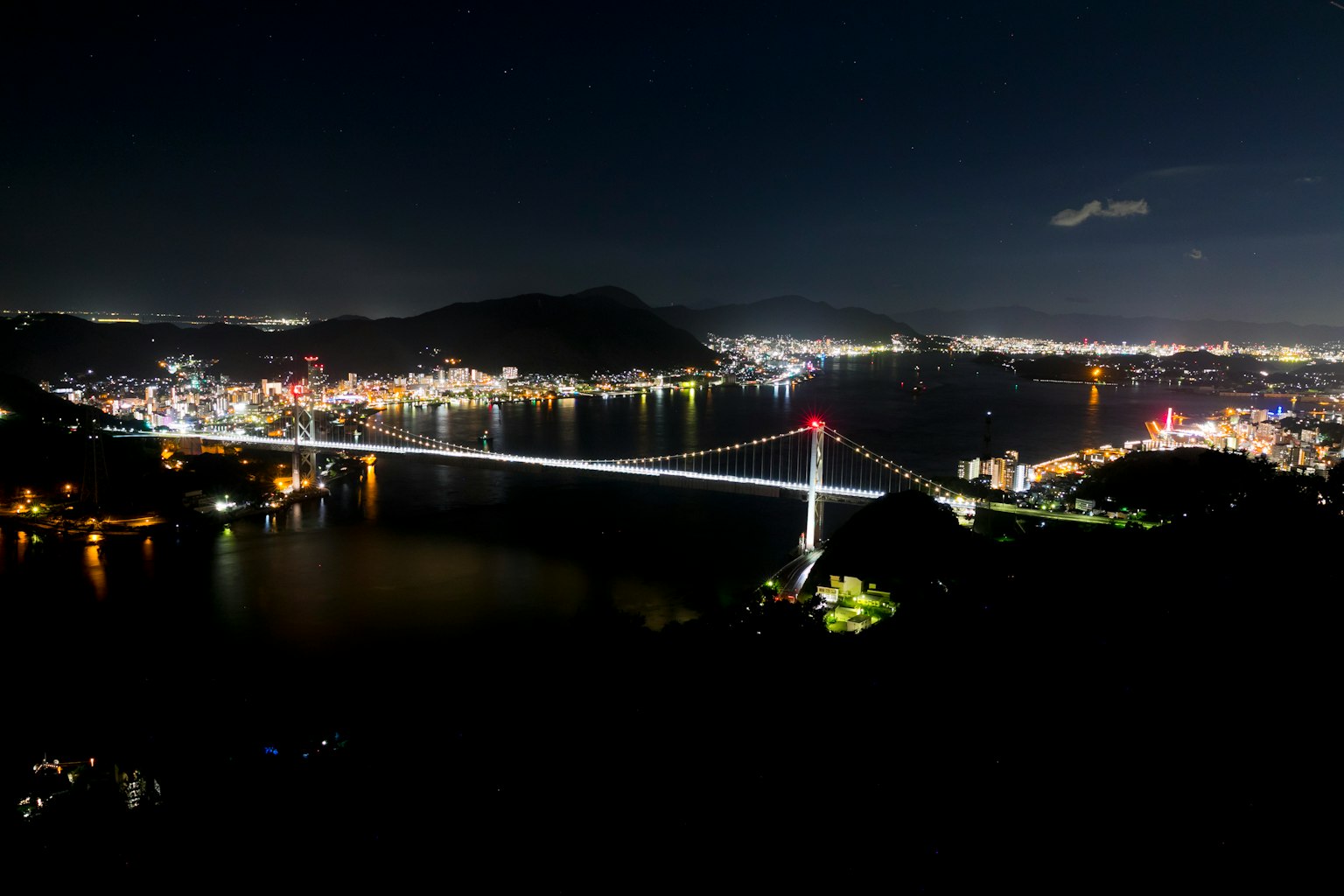 Beleuchtete Brücke und Stadtlichter bei Nacht
