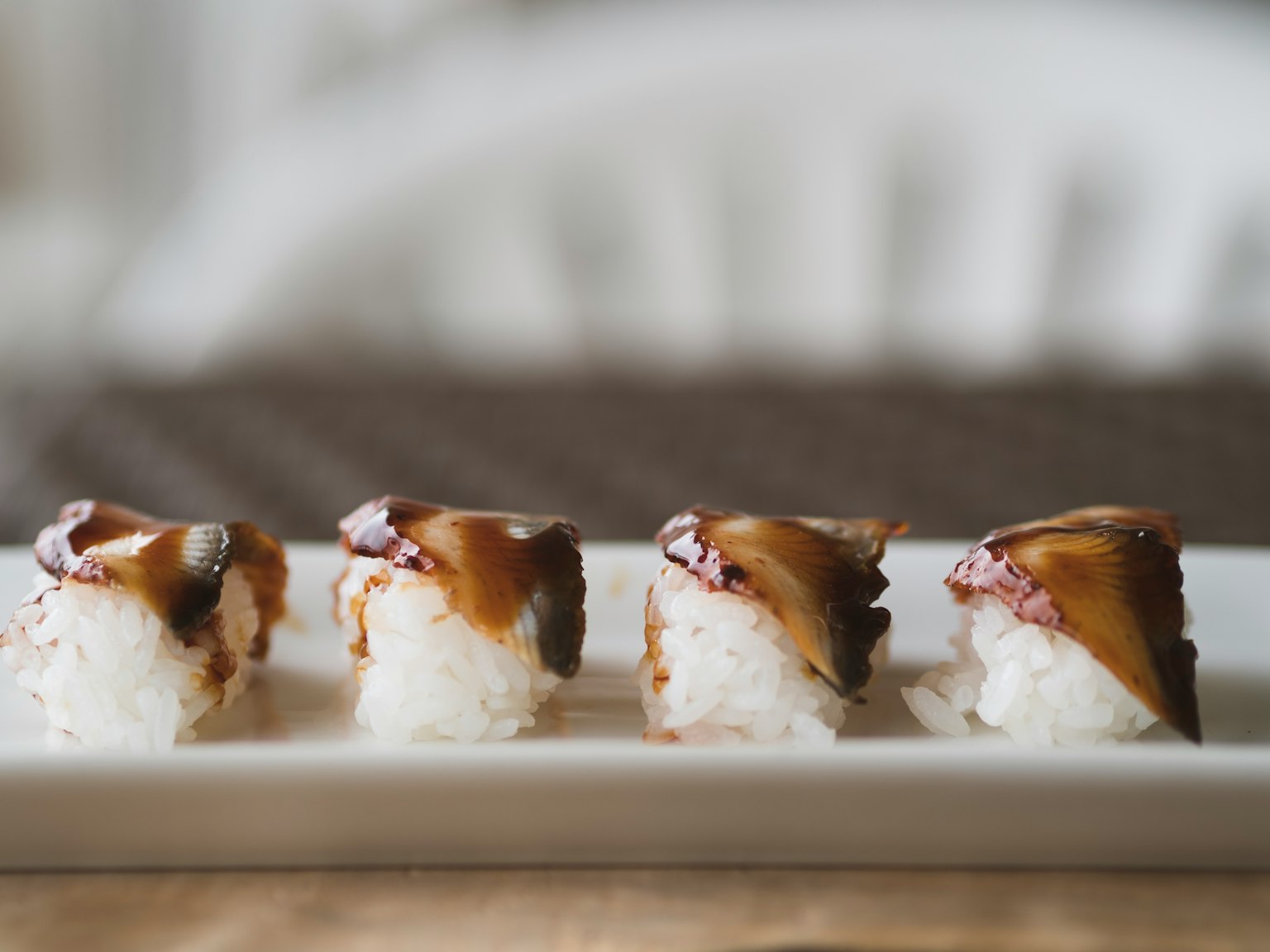 Eine Reihe von Sushi auf einem weißen Teller mit Lachs und süßer Sauce