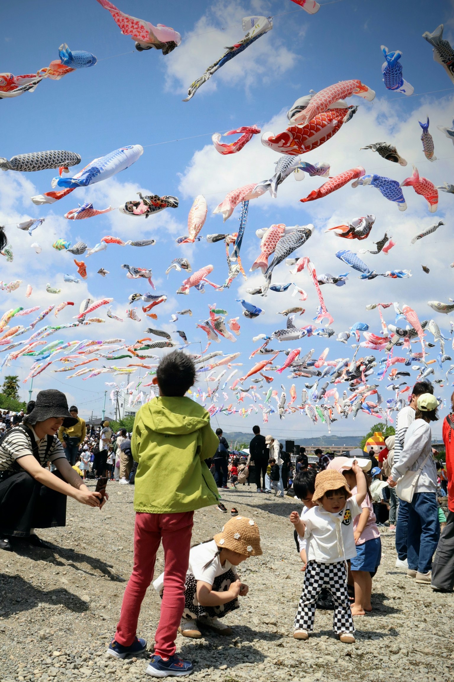 Trẻ em chơi dưới những koi nobori đầy màu sắc bay trong bầu trời xanh