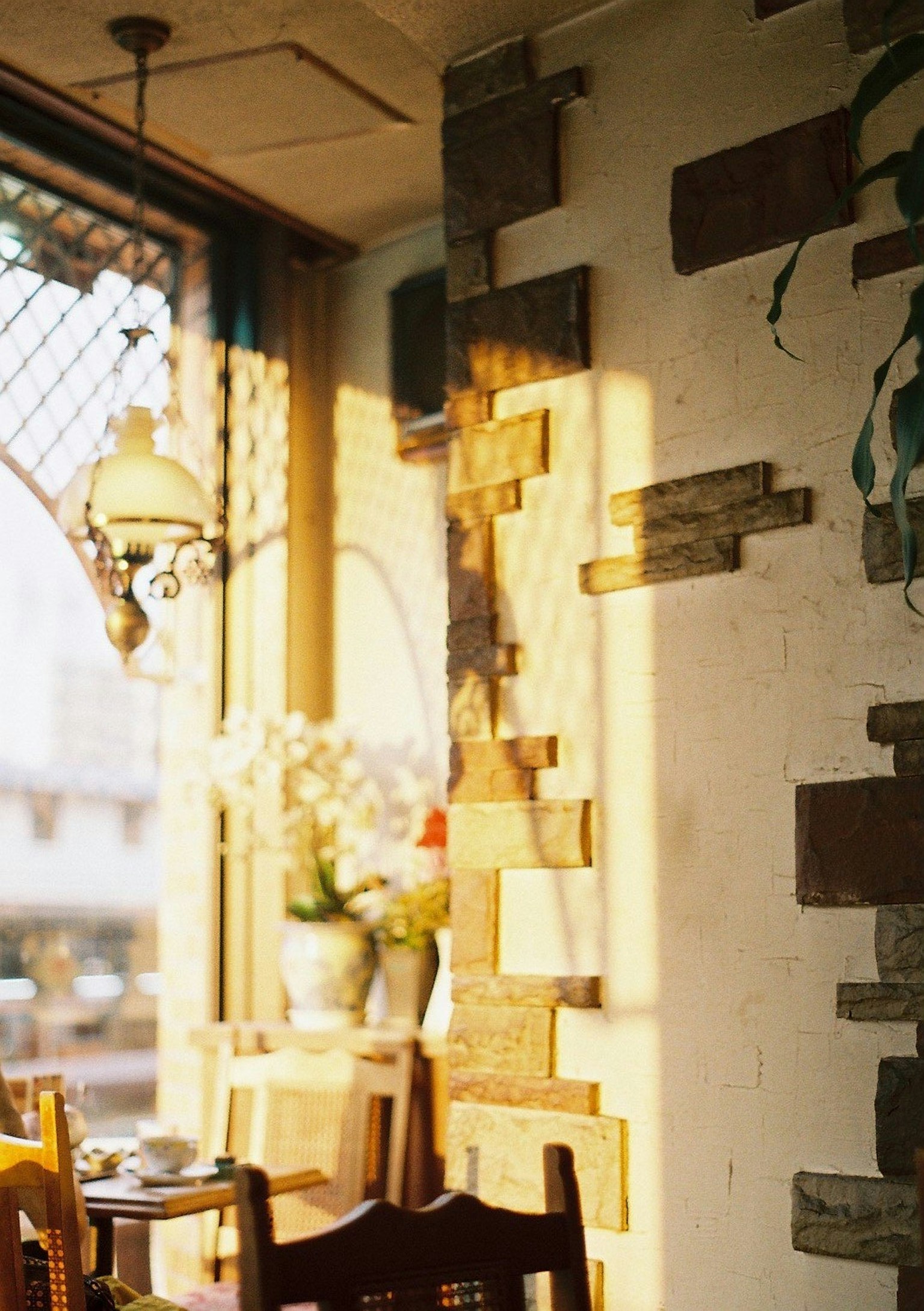 Gemütliches Café-Interieur mit warmem Licht, das durch Holzwanddekorationen und eine Blumenvase scheint