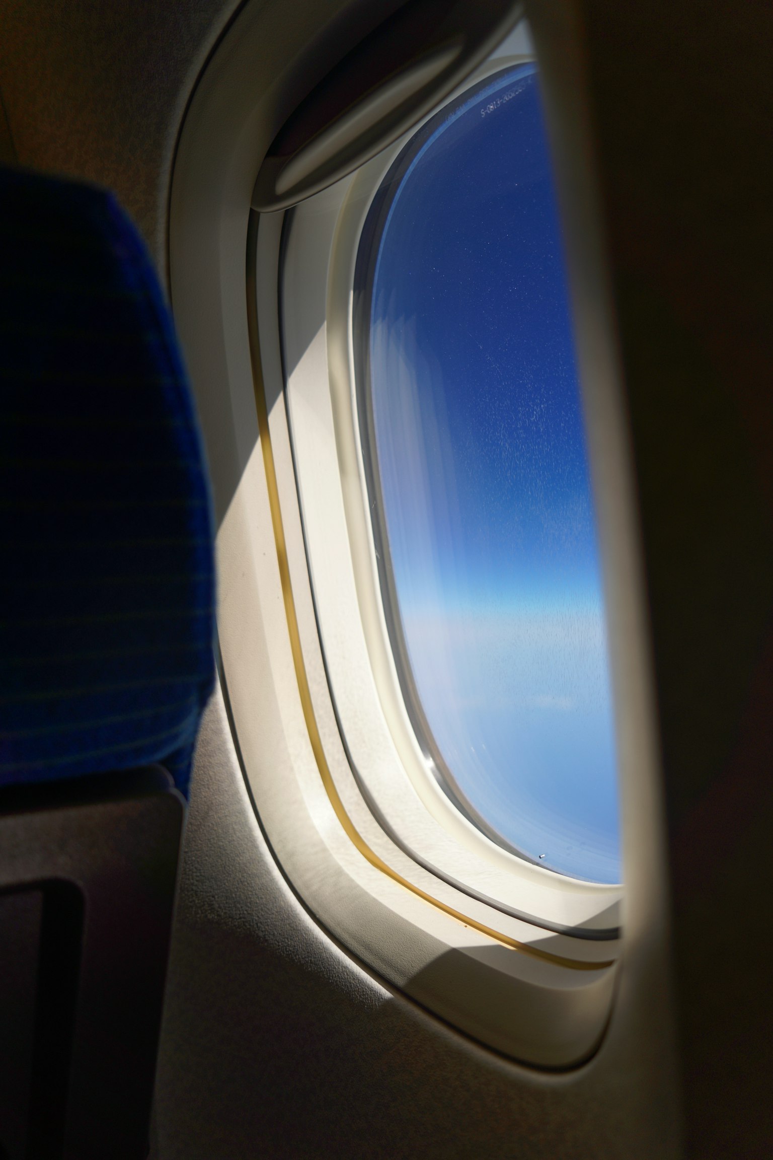 Vista del cielo azul claro y nubes a través de una ventana de avión
