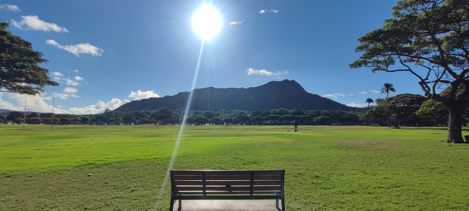 公园长椅俯瞰山景，阳光明媚，天空晴朗