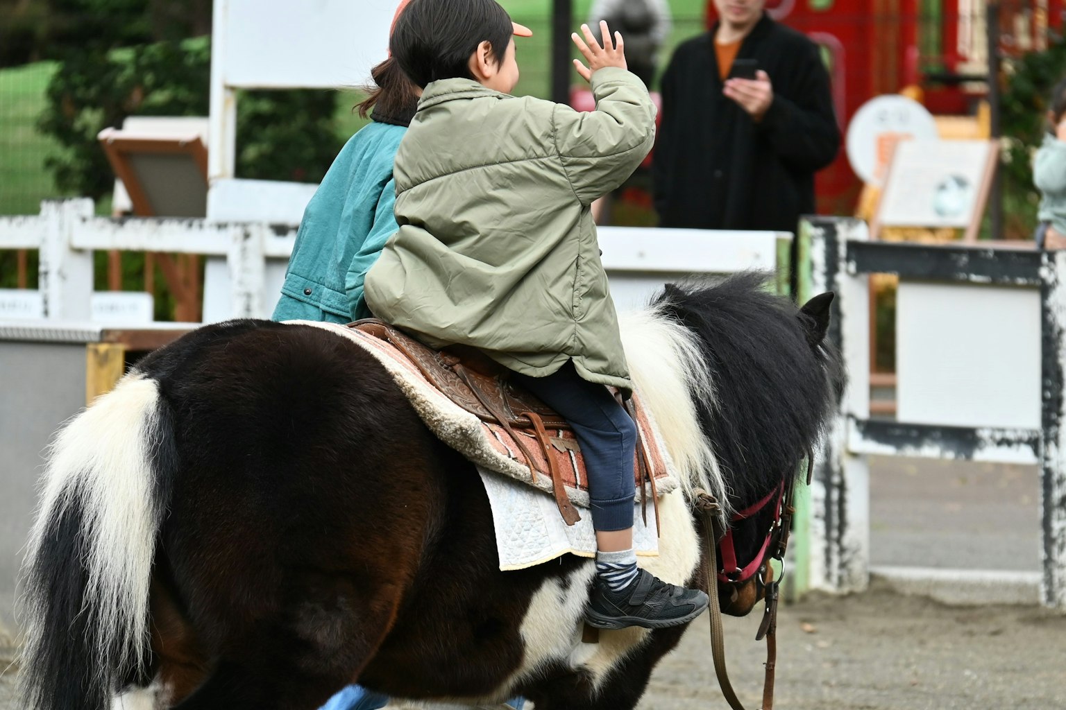 Un enfant agitant la main en montant un poney