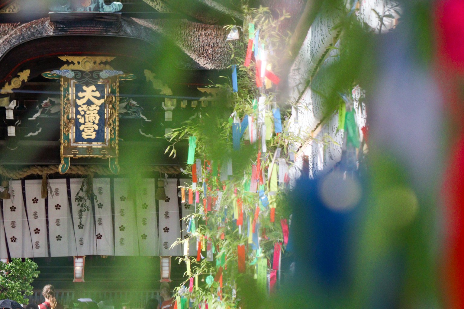 Tanzaku coloridos colgados de hojas de bambú con un edificio japonés tradicional al fondo
