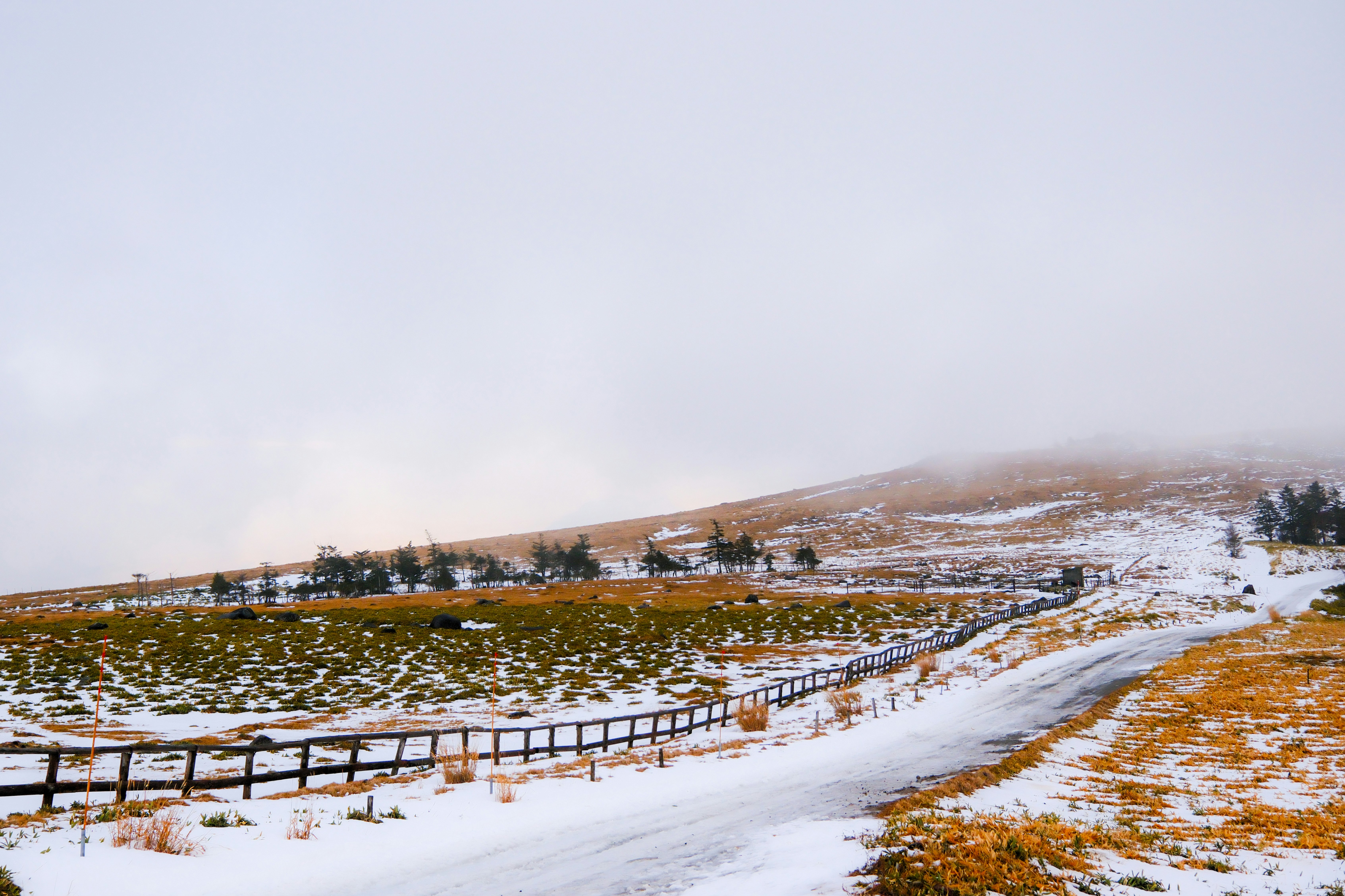 Schneebedeckte Hügel mit nebliger Landschaft