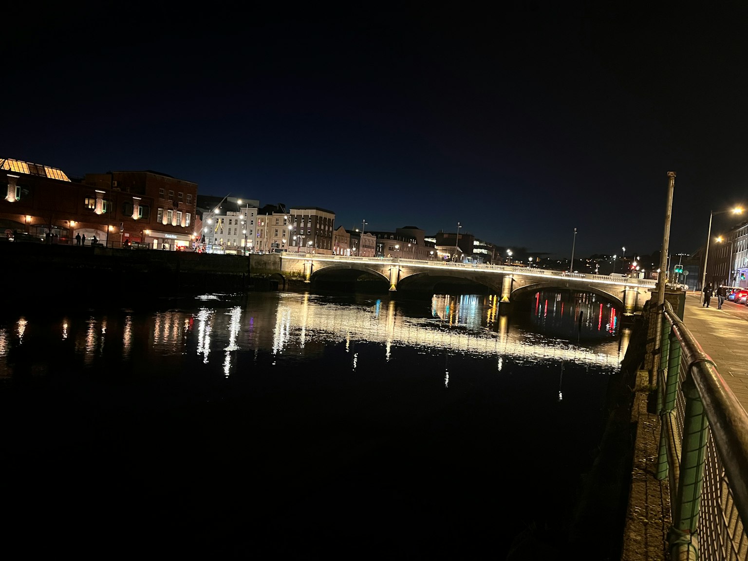 Vista notturna di un bel ponte su un fiume con le luci degli edifici circostanti
