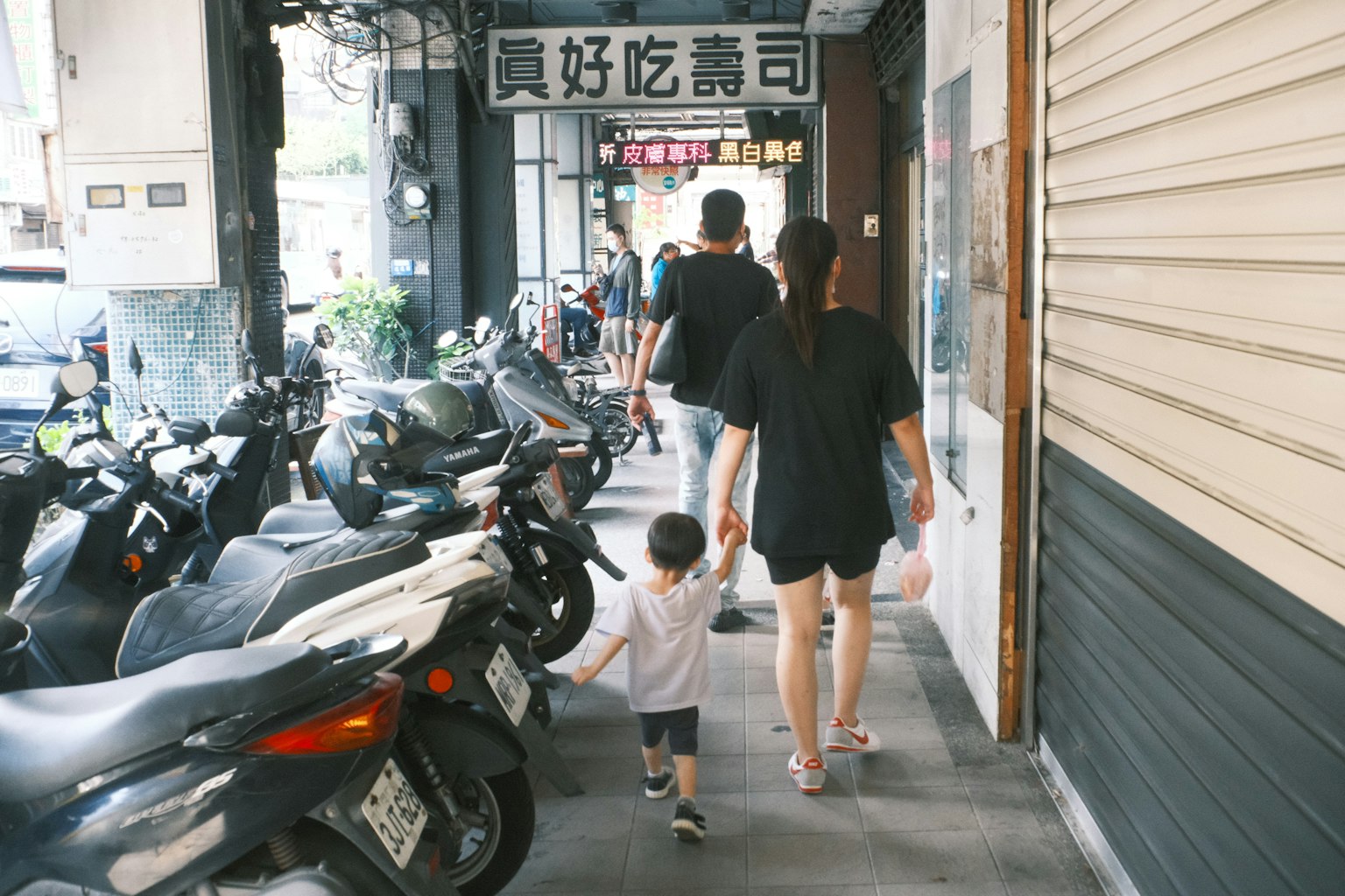 Un genitore e un bambino che camminano mano nella mano lungo una strada fiancheggiata da motociclette