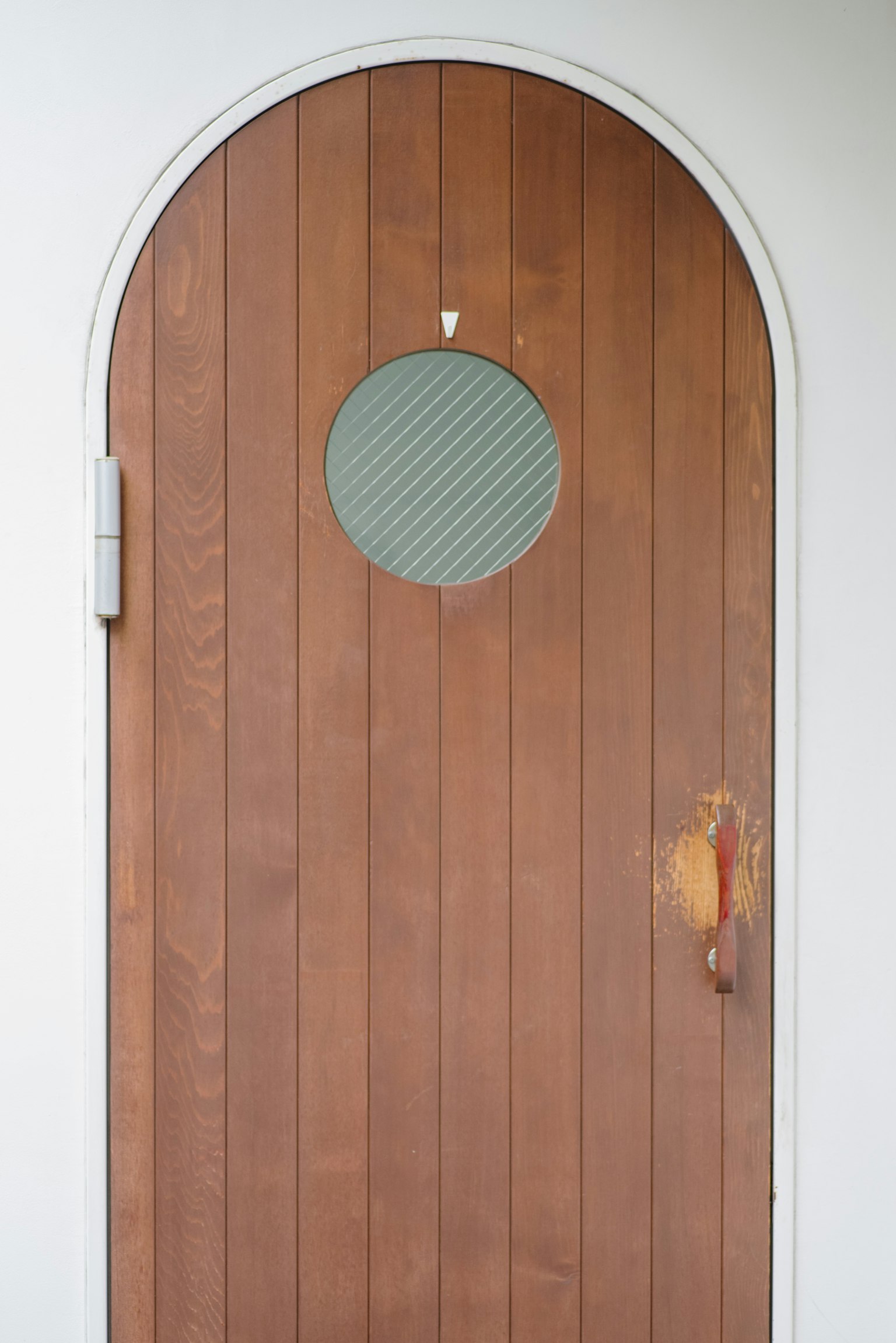 Porta in legno con finestra circolare e design ad arco unico