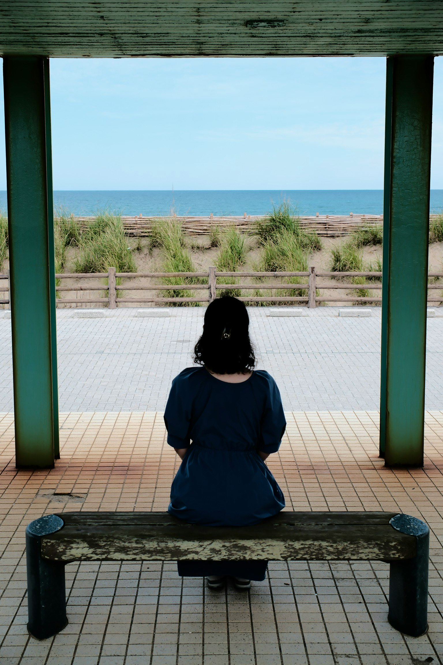 海を望むベンチに座る女性