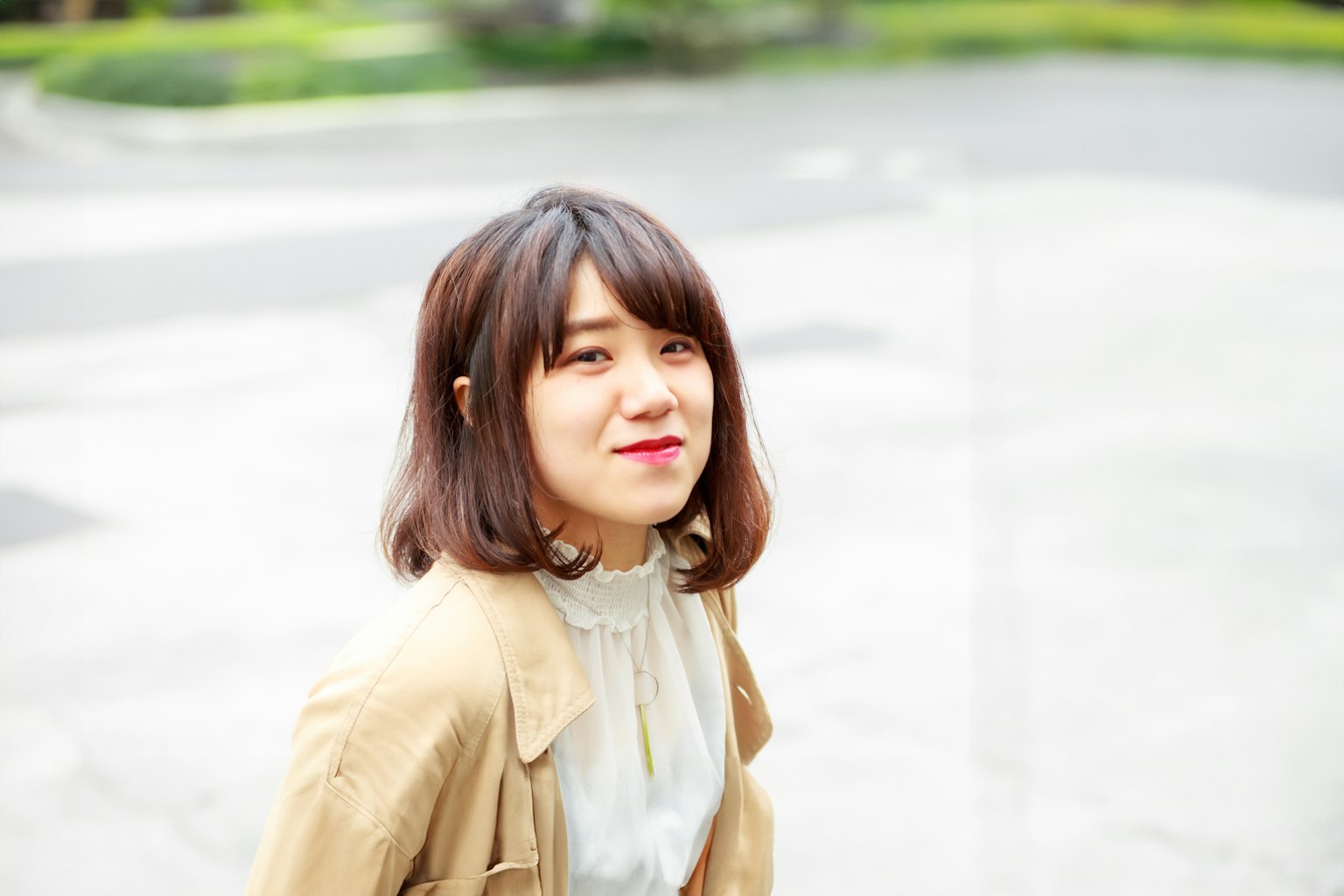 Eine Frau lächelt in lässiger Kleidung vor einem natürlichen Hintergrund