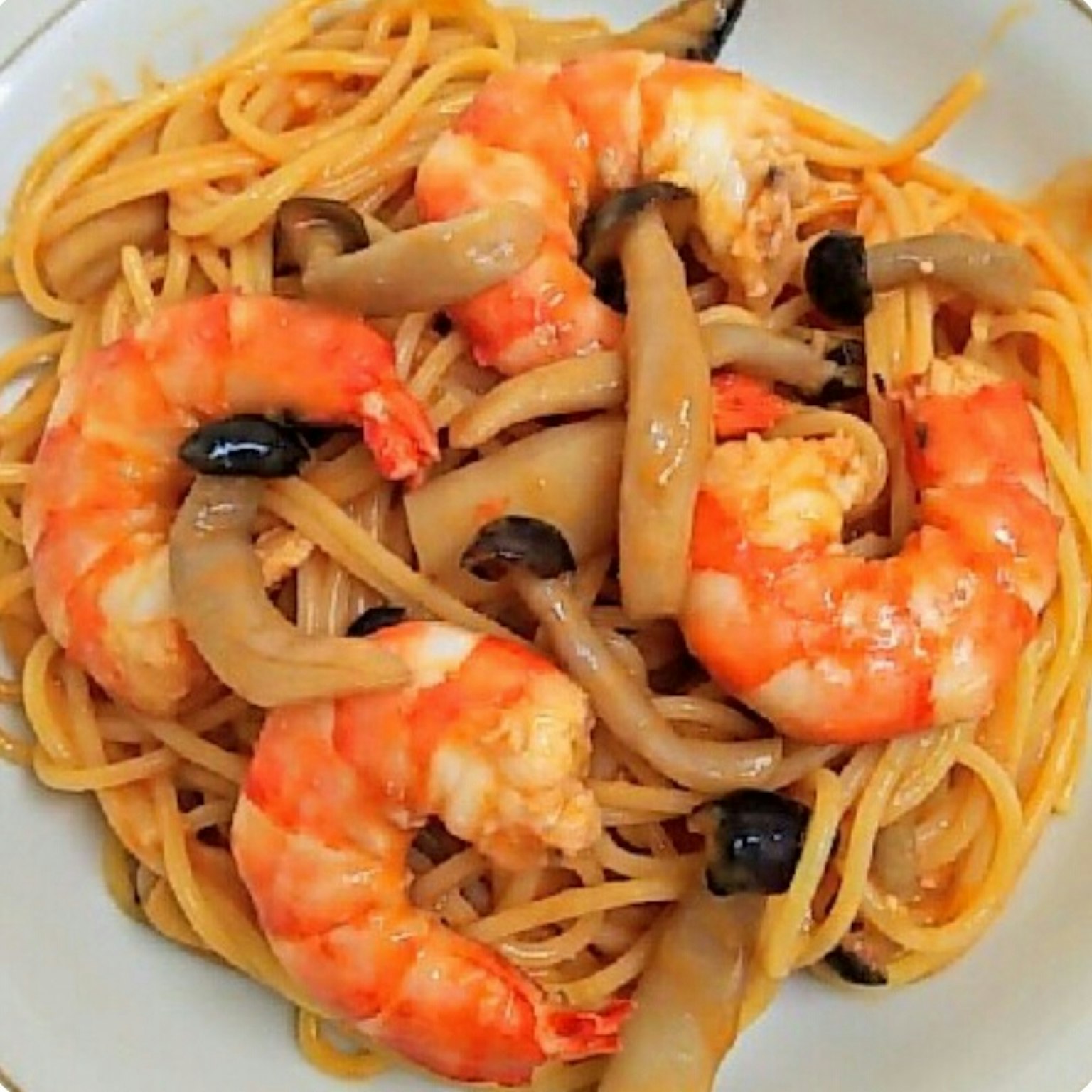 Primo piano di un piatto di spaghetti con gamberi e funghi