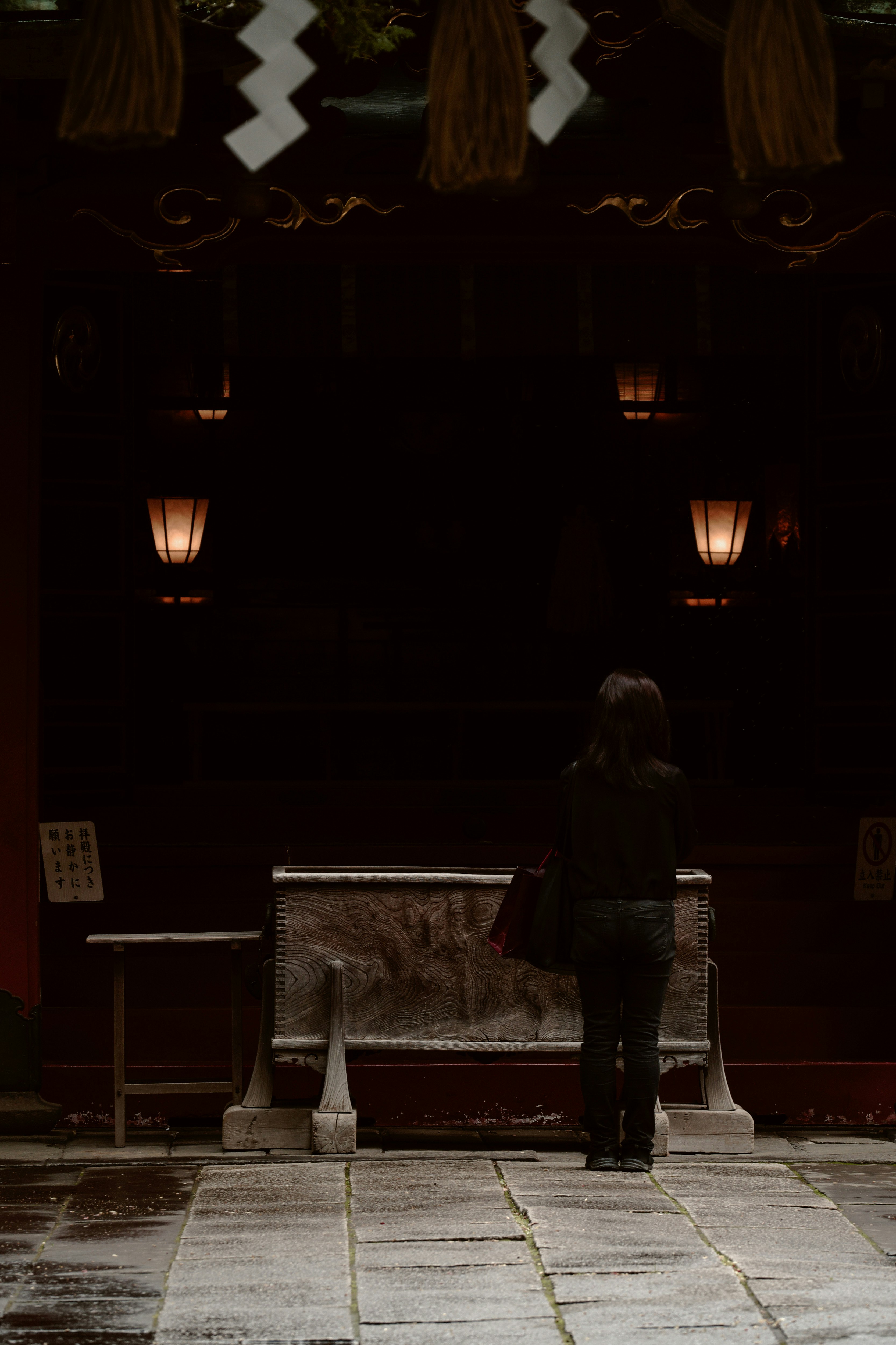 night shrine grounds where a worshipper performs temizu at the stone steps