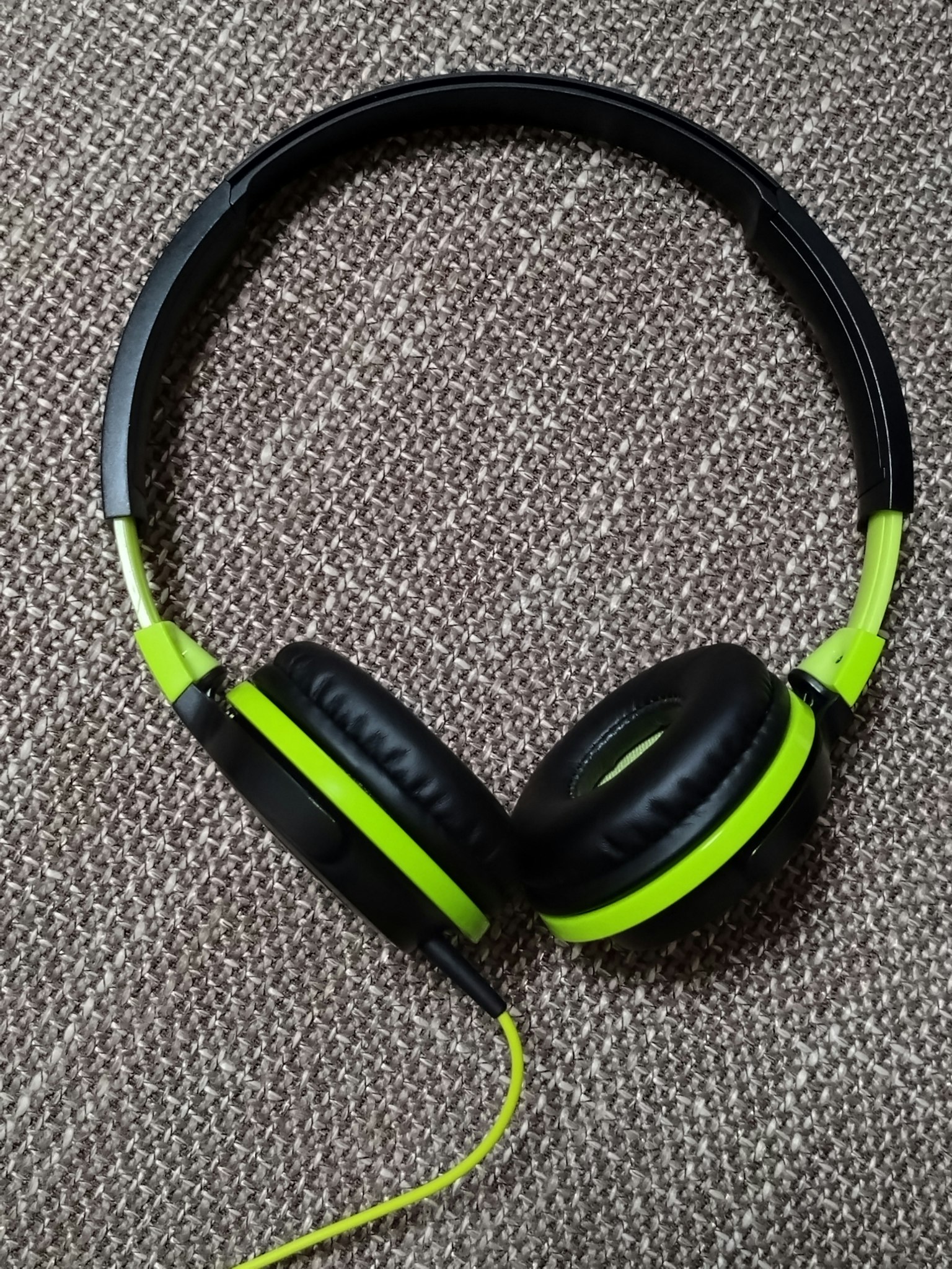 Black and green headphones resting on a textured background