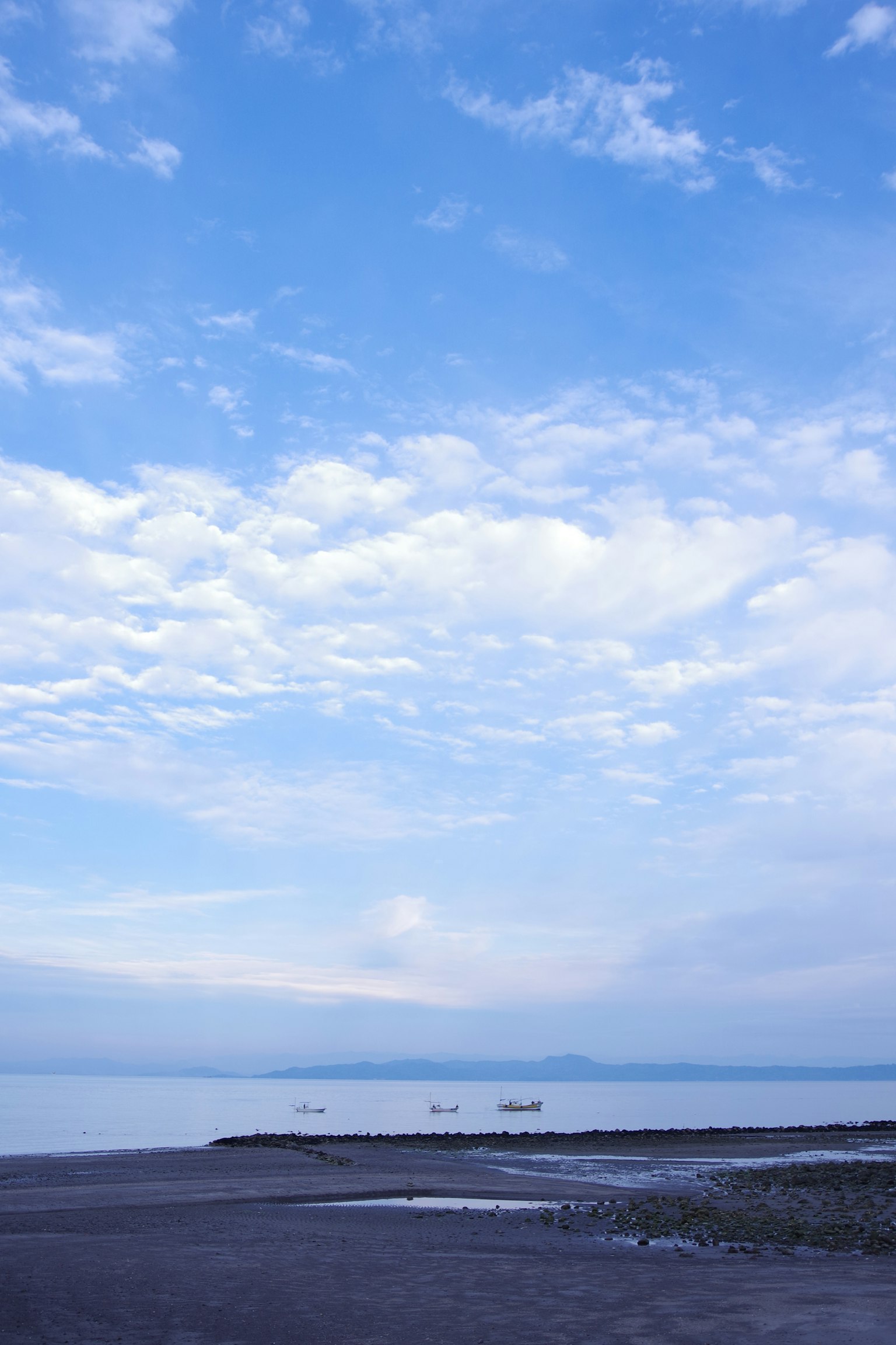 平靜的海面下藍天與遠處的船隻