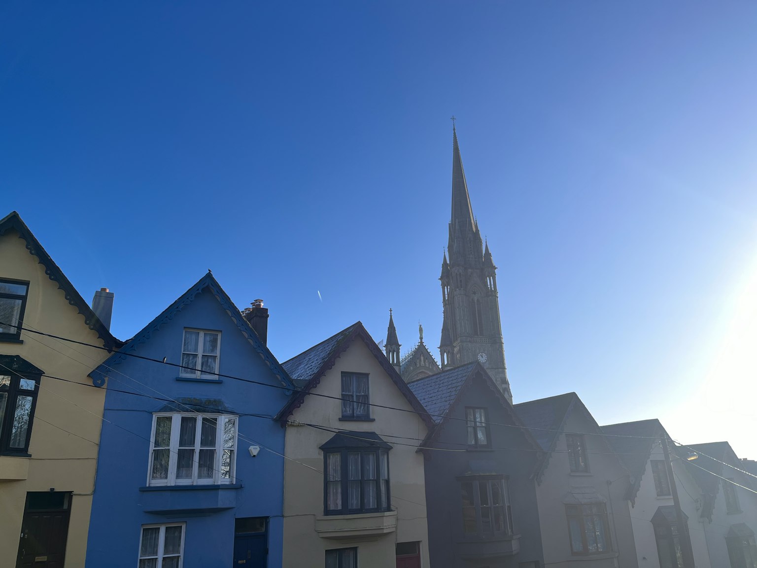 Row of colorful houses with a tall spire against a clear blue sky