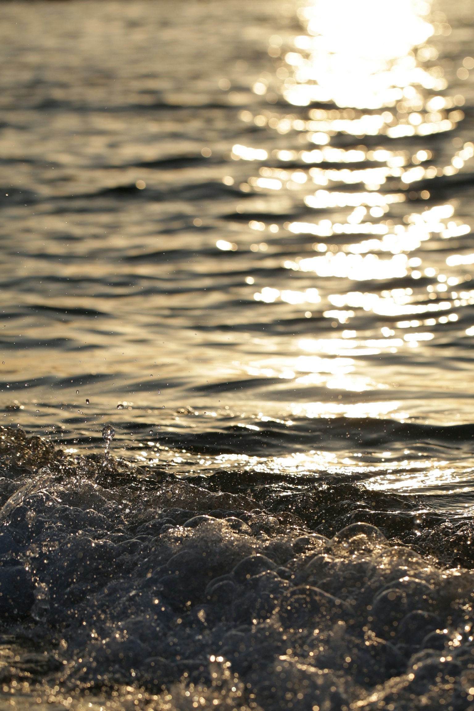 Imagen de olas del océano con la luz dorada del sol reflejándose en la superficie del agua
