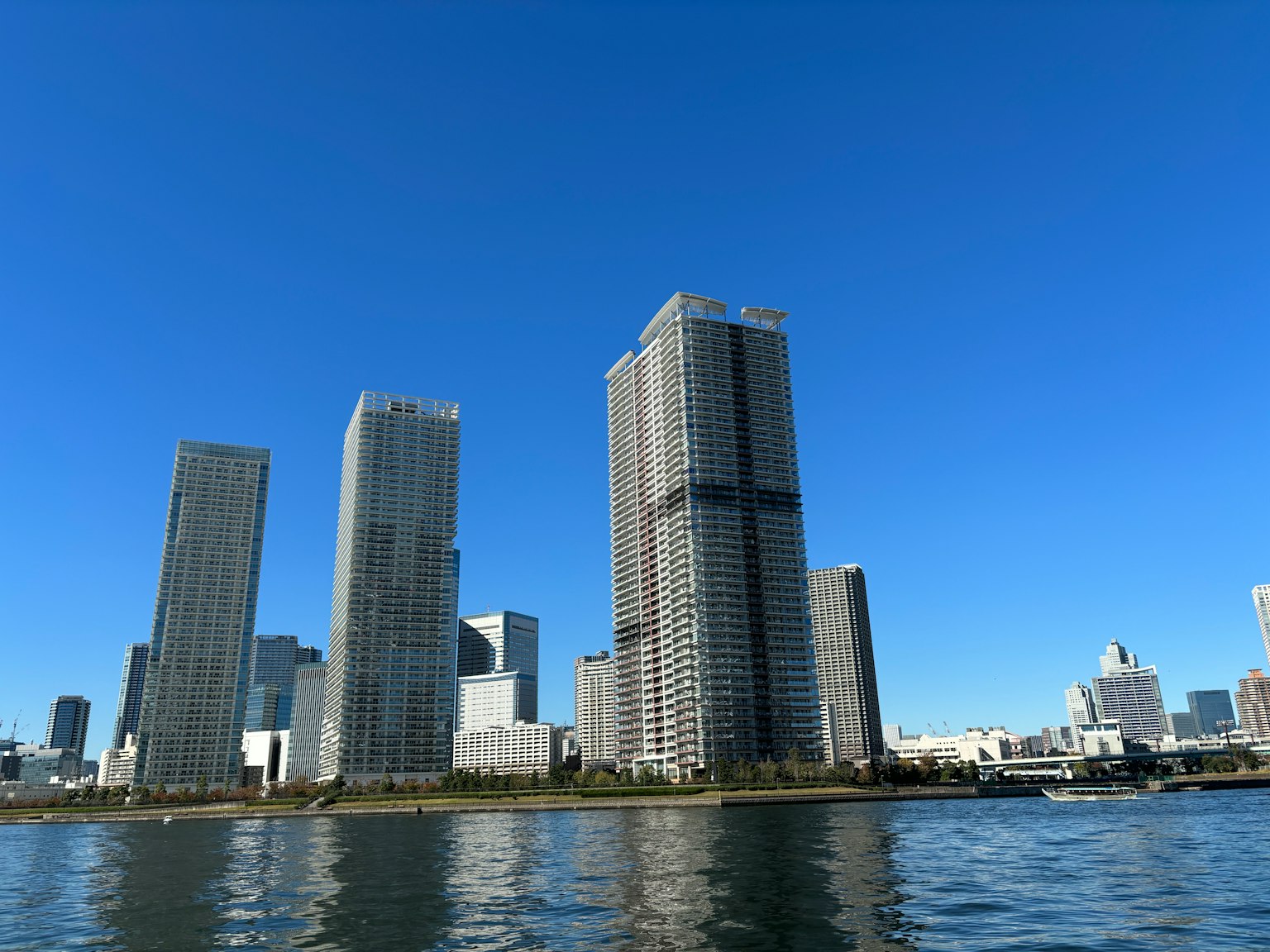 在晴朗藍天下平靜水面上倒映的摩天大樓