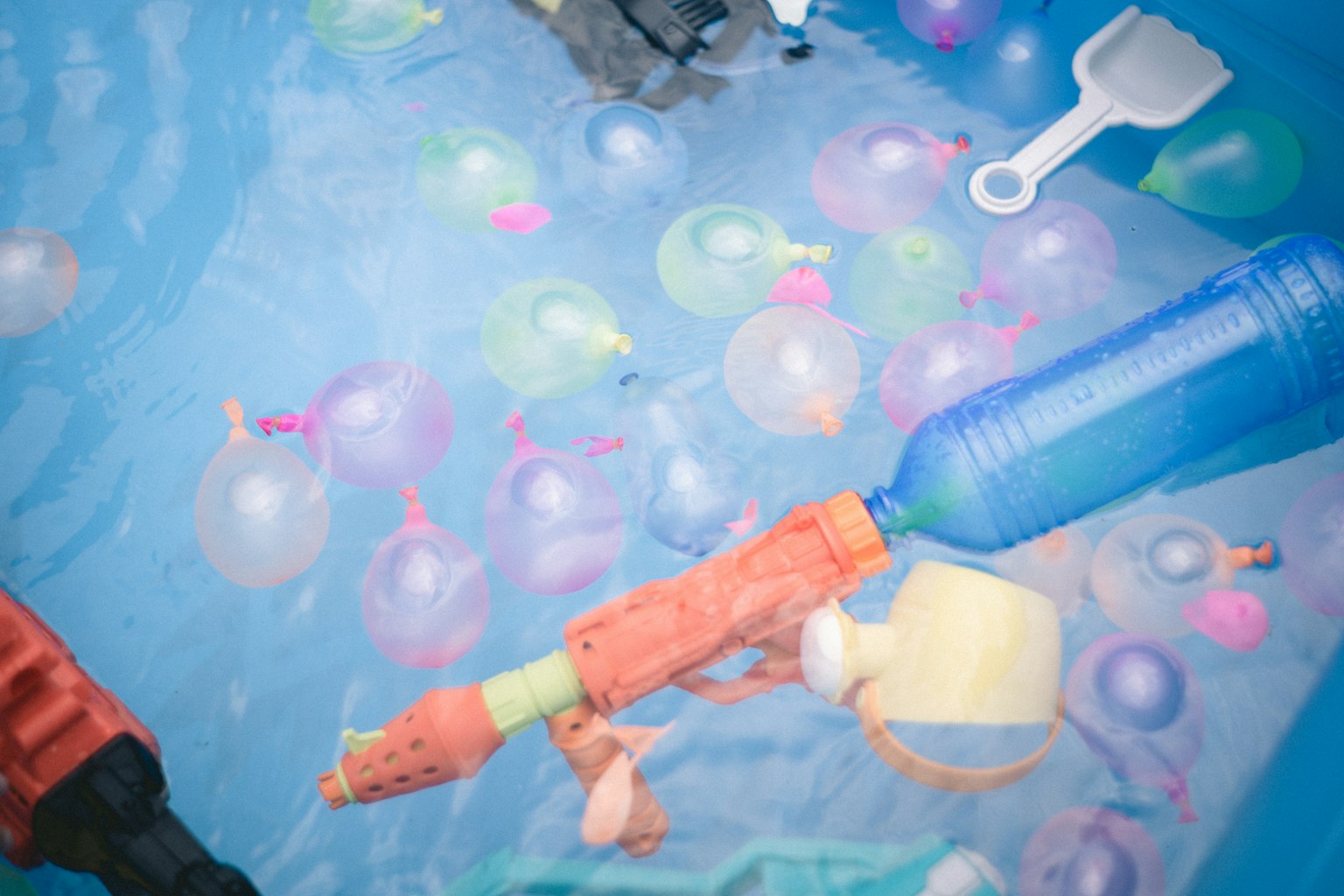 Globos de agua coloridos y juguetes flotando en una piscina azul