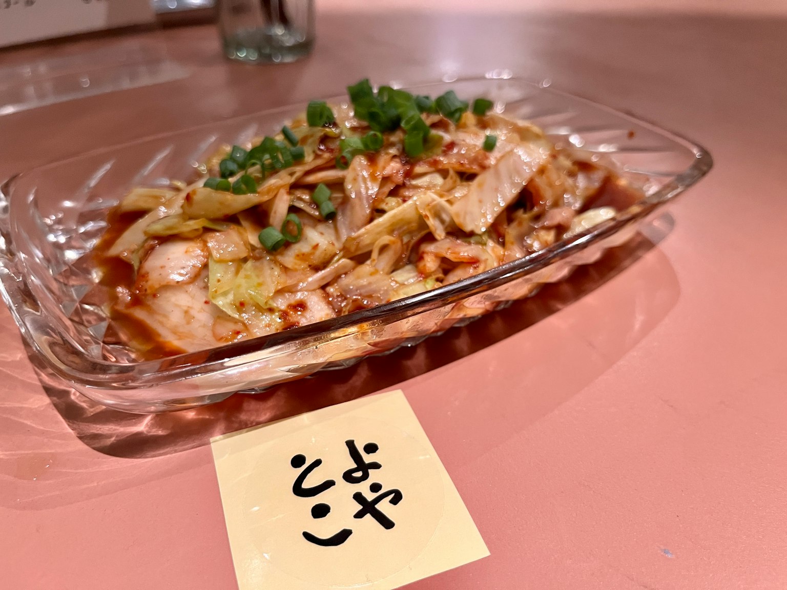 透明盘子中盛放的鸡肉和卷心菜菜肴，上面点缀着青葱